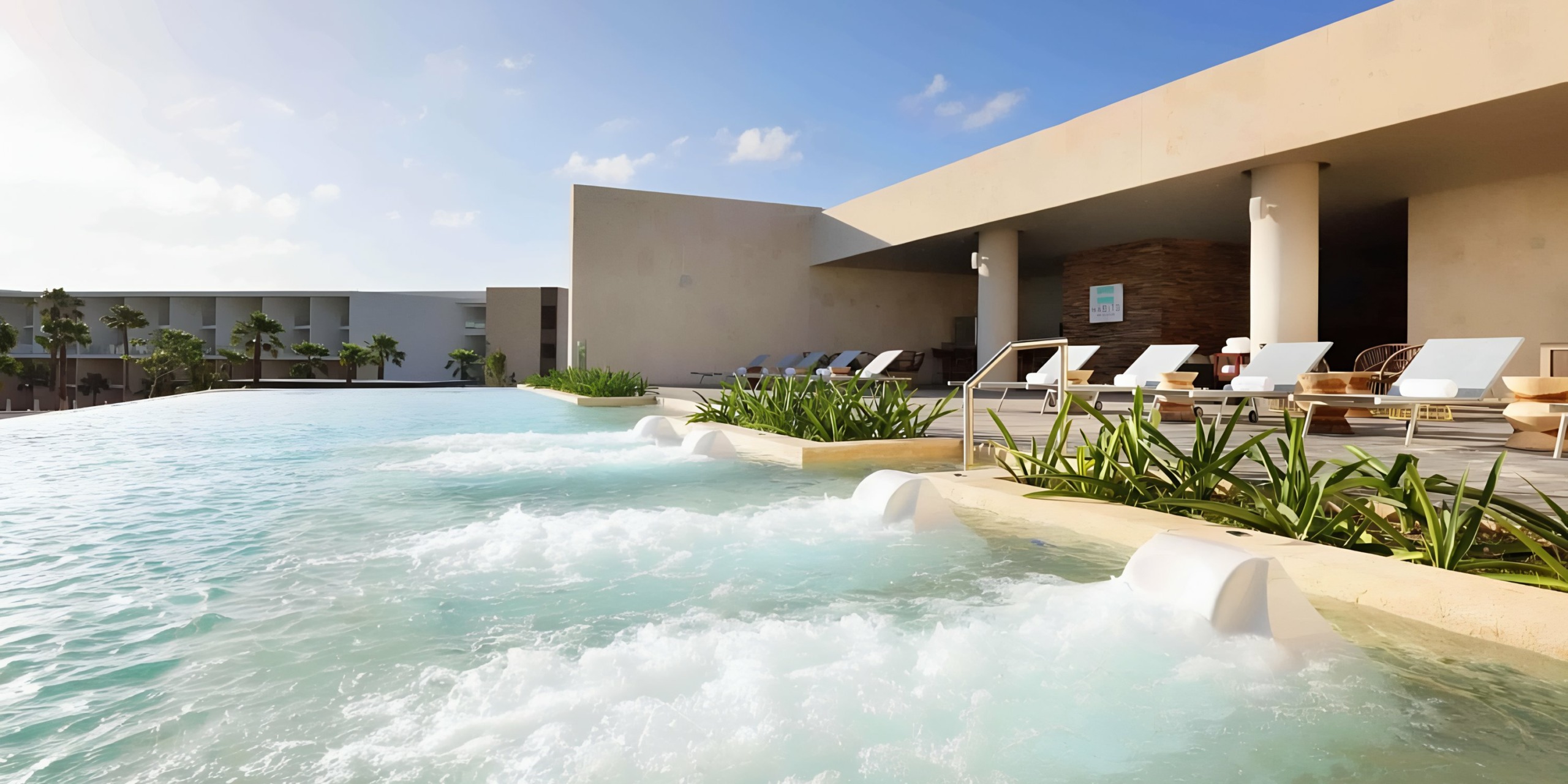 Modern infinity pool at Grand Palladium Costa Mujeres with sun loungers and serene water features.