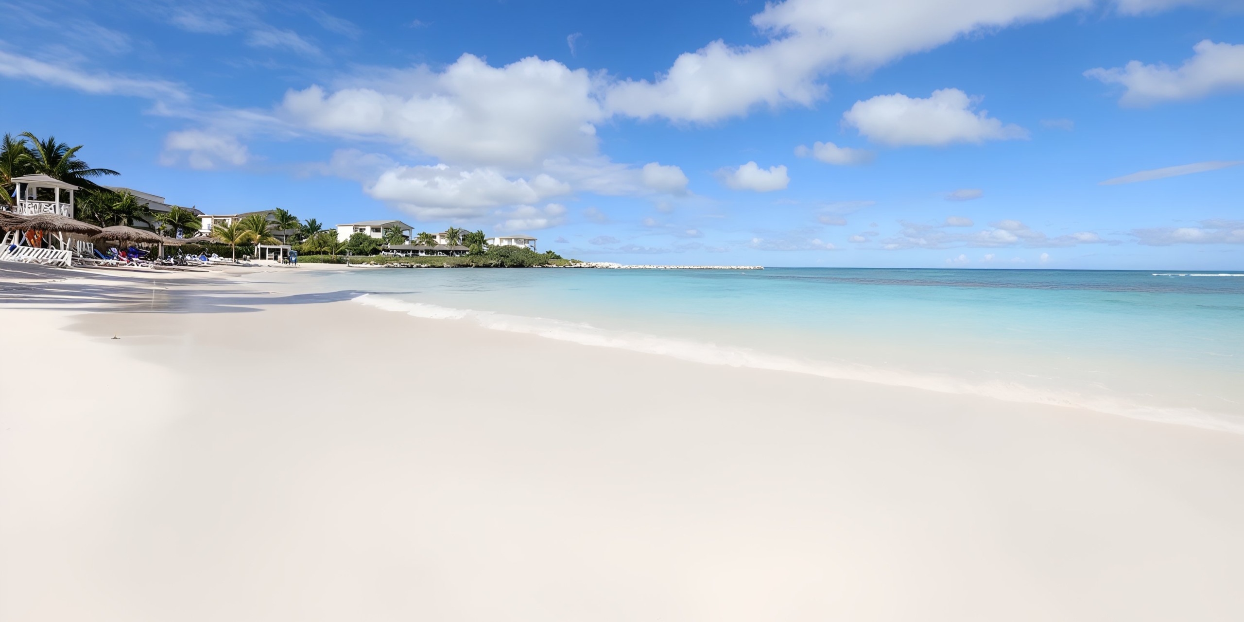 The tranquil beach at Grand Palladium Lady Hamilton features soft white sand, crystal-clear turquoise waters, and a sky sprinkled with fluffy clouds—creating a perfect setting for a dream wedding.