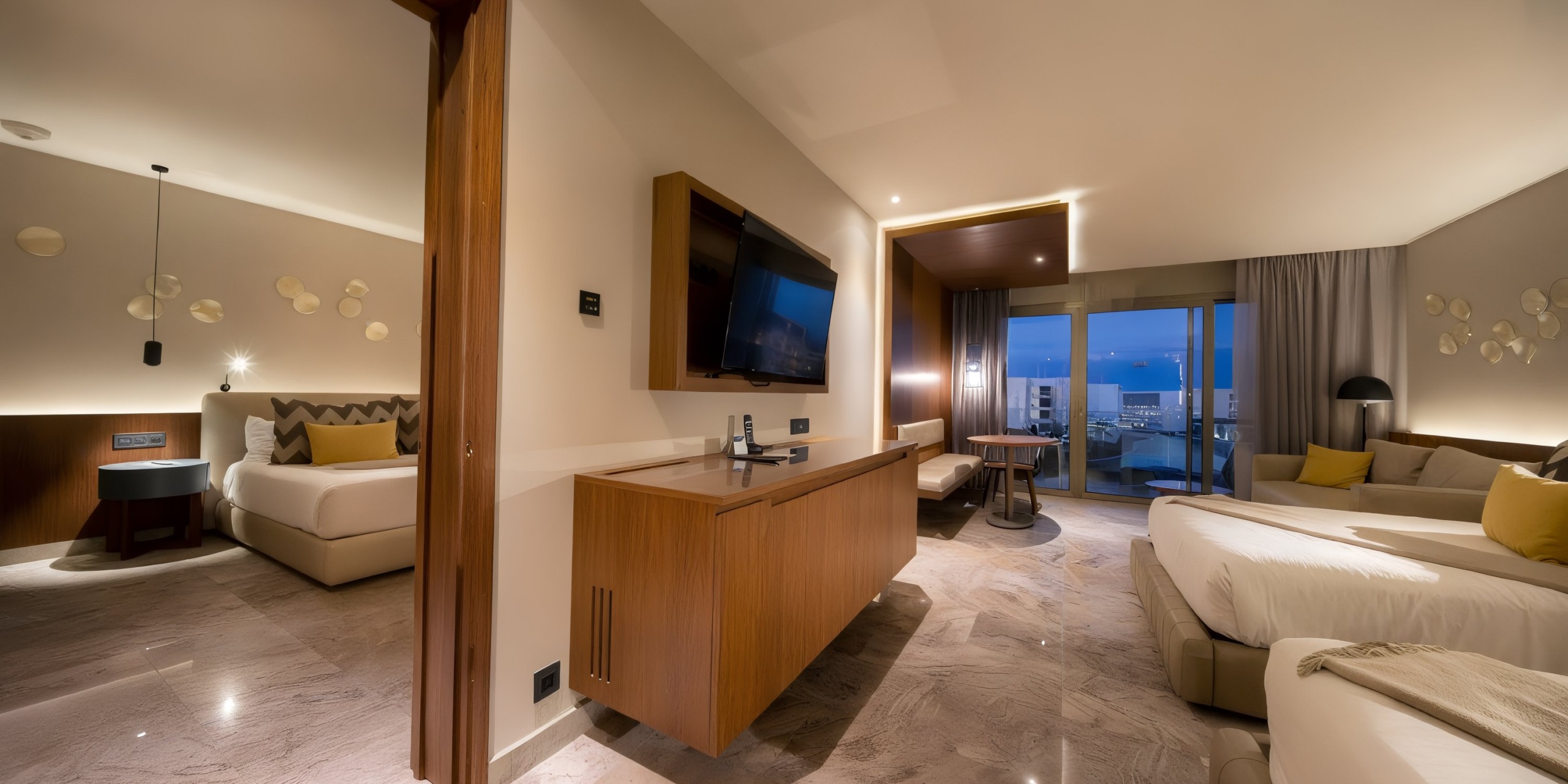 Experience a contemporary room at the Grand Palladium Costa Mujeres, featuring twin beds, a wall-mounted TV, a desk, and a sliding glass door that opens to a balcony with breathtaking sea views.