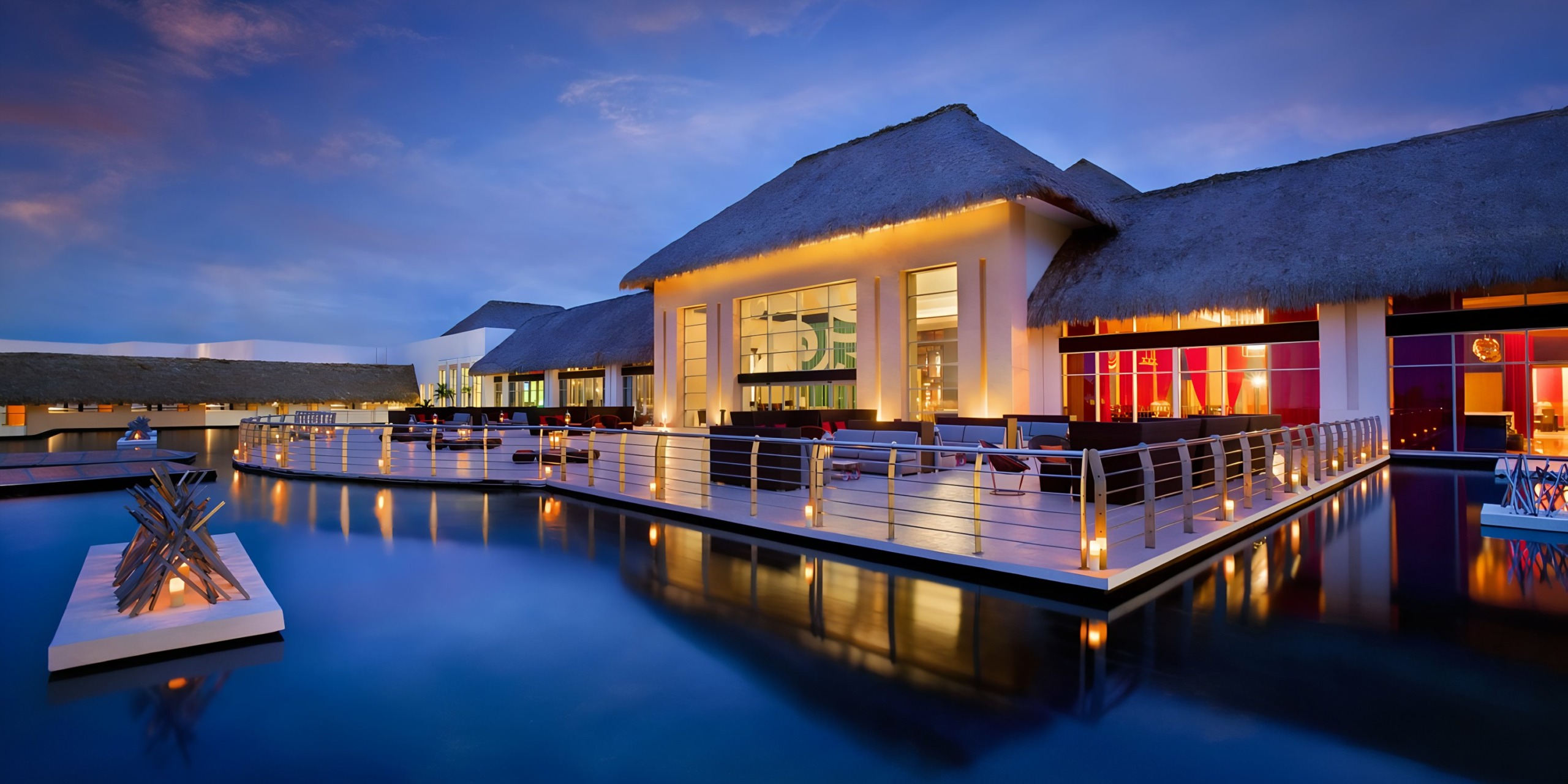 Hard Rock Punta Cana overwater villas lit up at twilight with a serene ocean view.