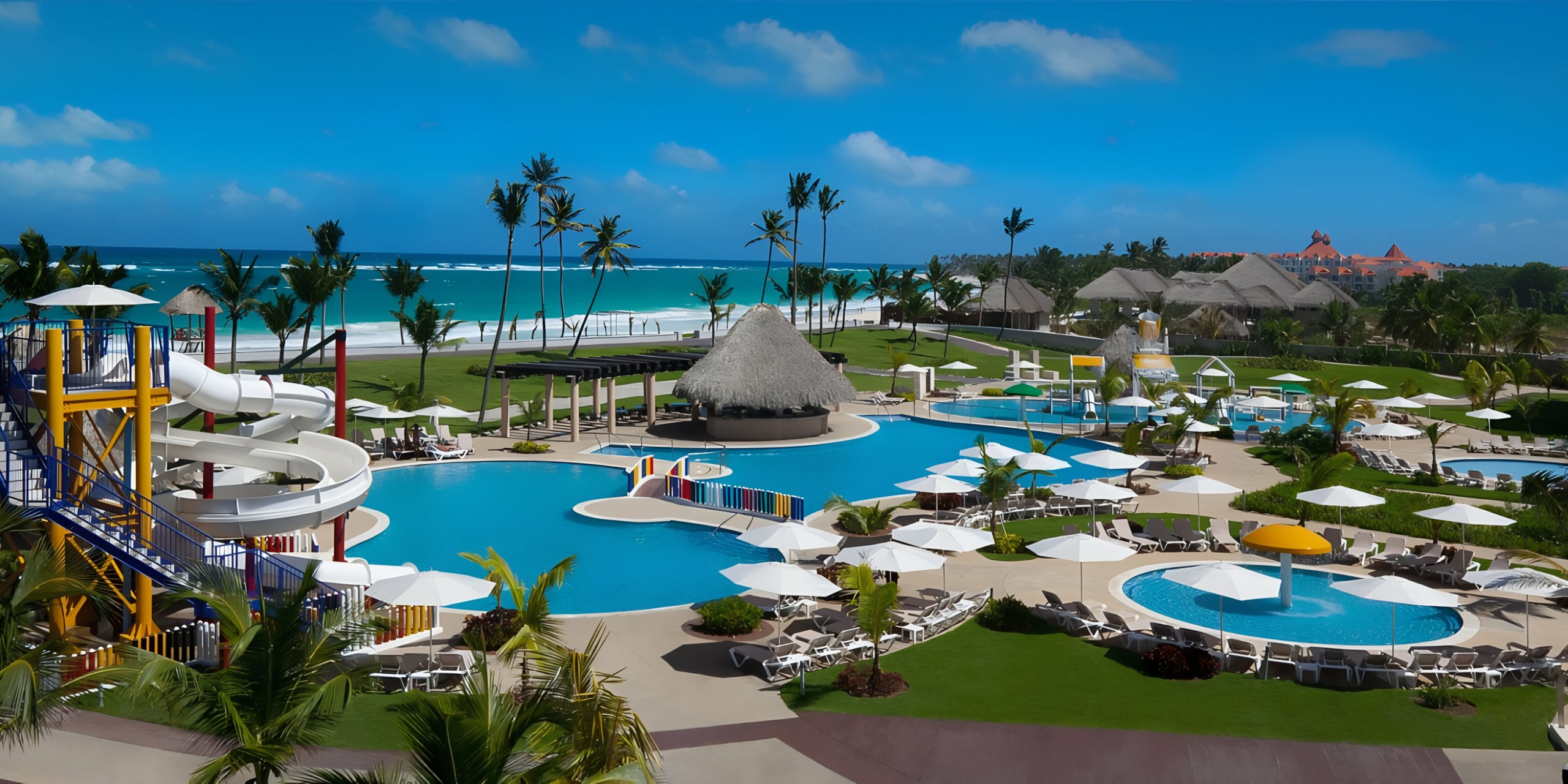 Hard Rock Punta Cana resort with a swimming pool, water slides, and palm trees overlooking a beach.
