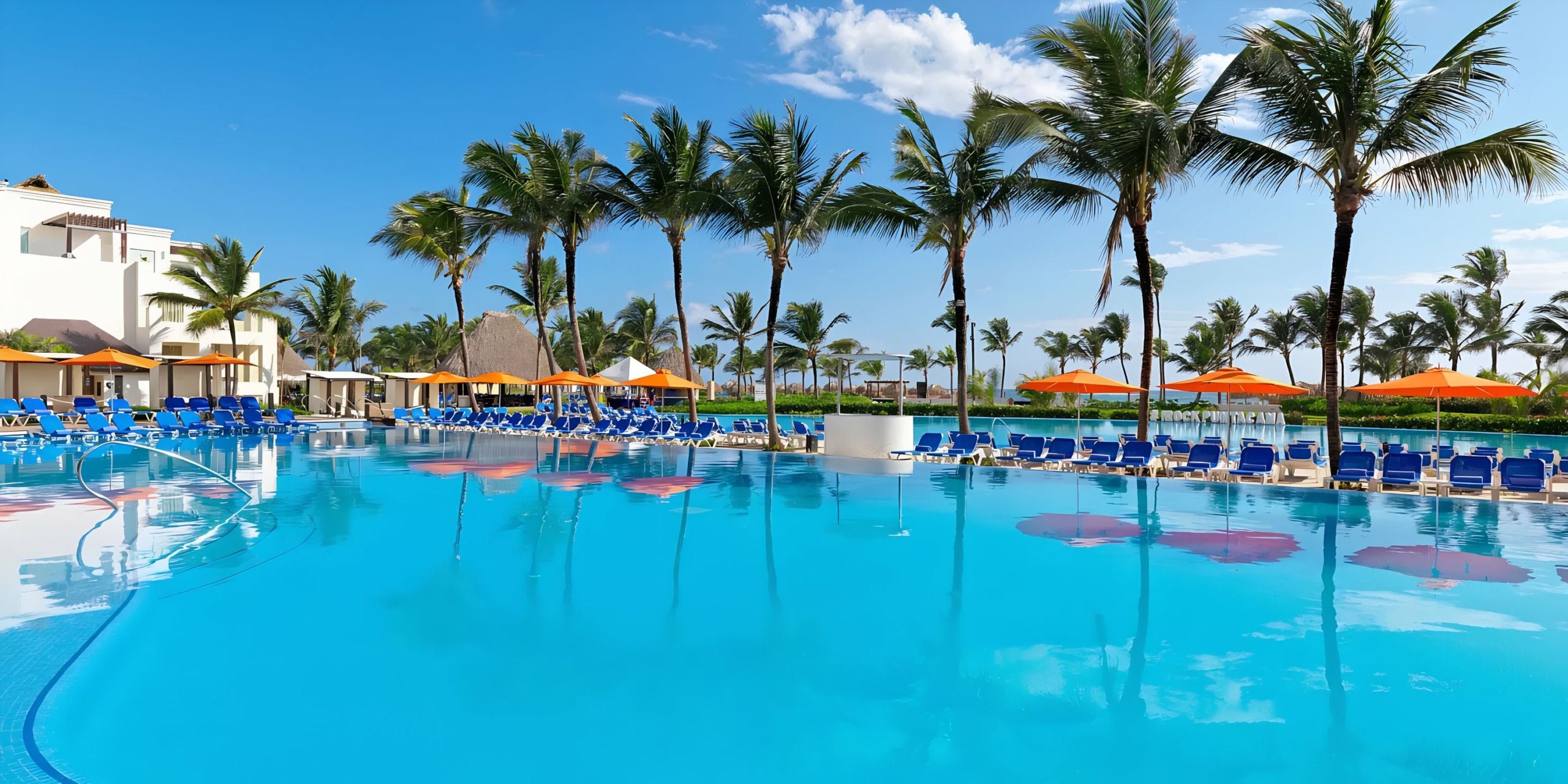 A Hard Rock Punta Cana resort pool flanked by palm trees and loungers under a clear blue sky.