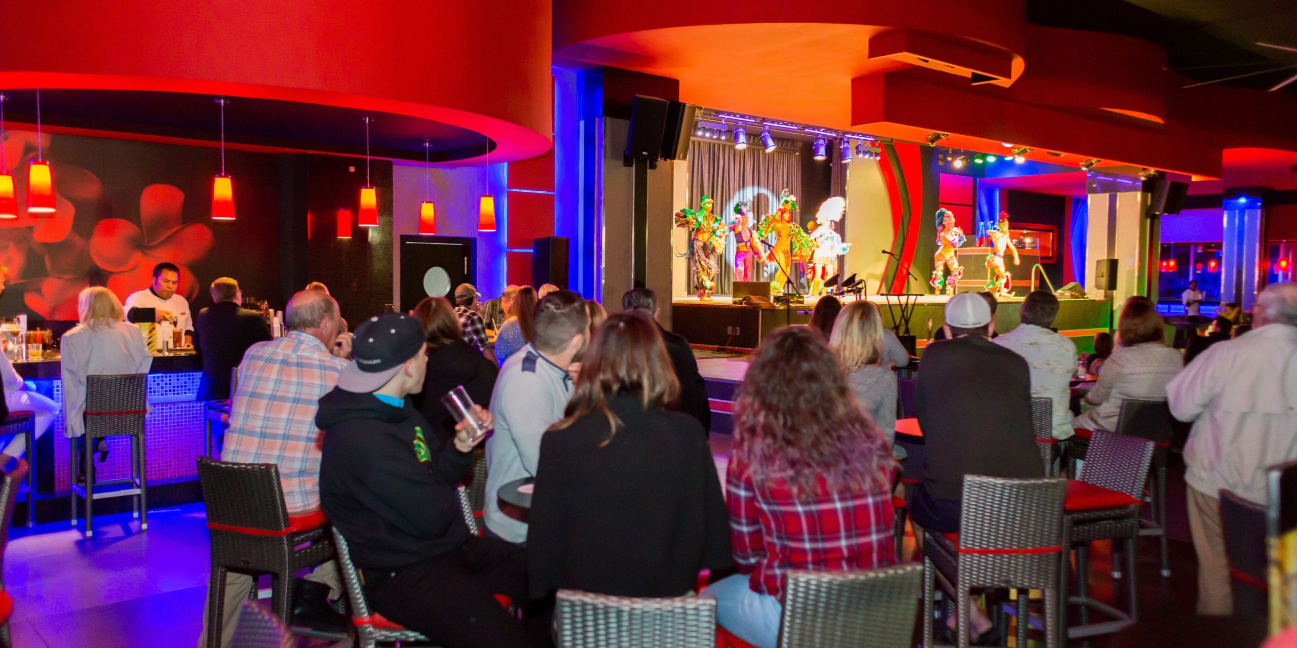 Guests at the Hotel Riu Palace Cabo San Lucas enjoy a lively bar atmosphere while watching a dazzling performance on stage.