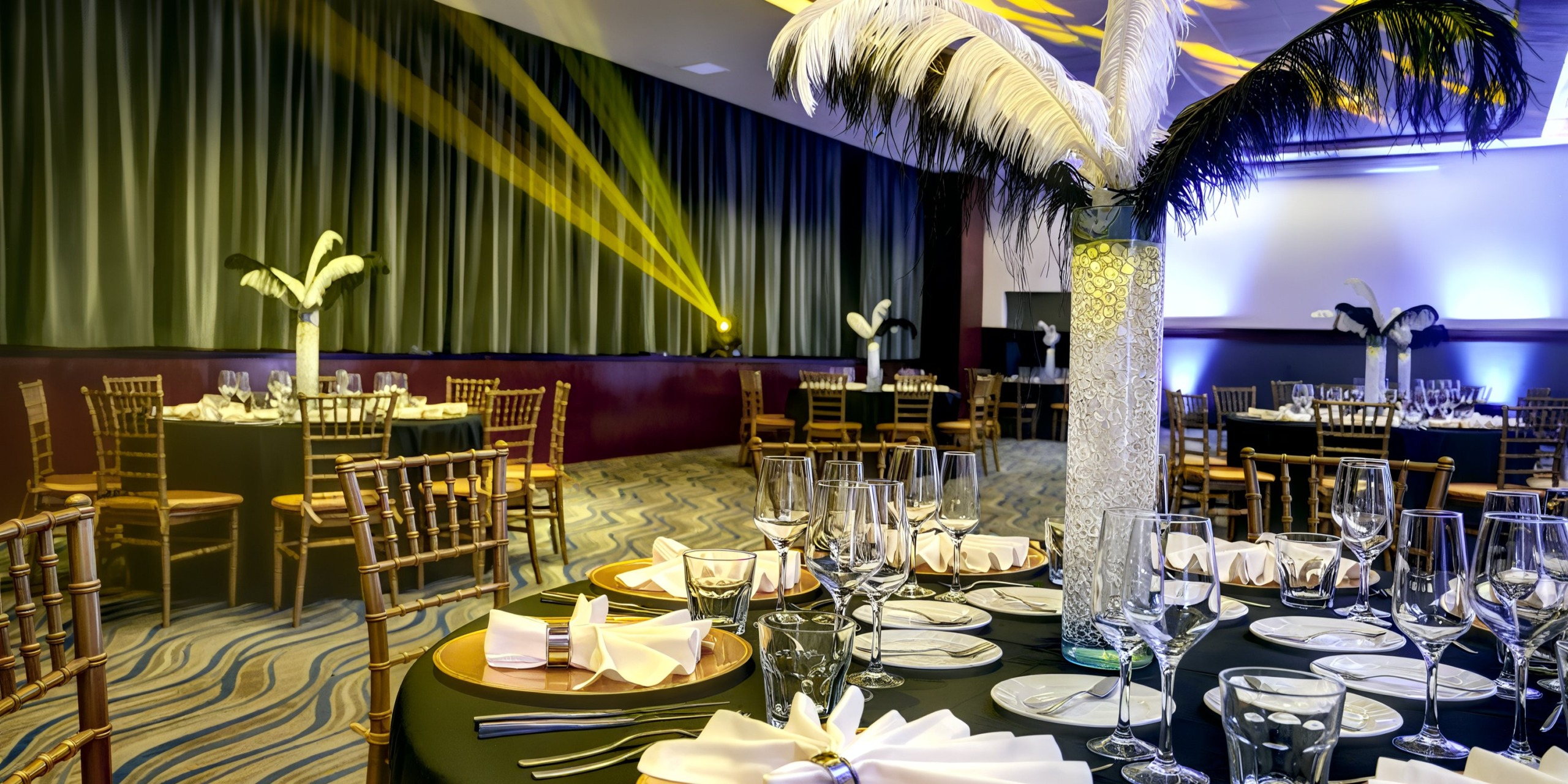 At the Royalton Riviera Cancun, the wedding venue is beautifully arranged with round tables, exquisite feather centerpieces, and soothing ambient lighting.