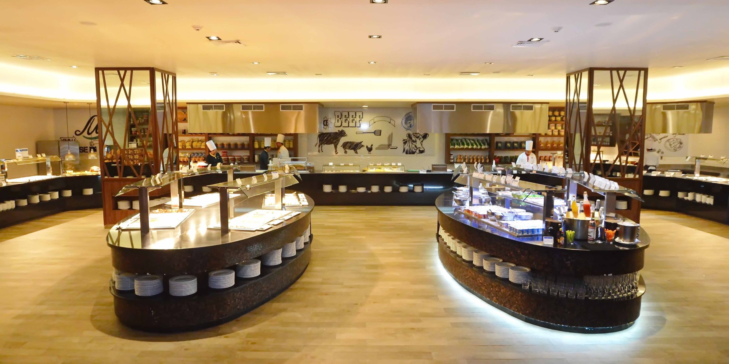 Located at the Royalton Riviera Cancun, this spacious, modern buffet restaurant boasts two central islands offering a wide variety of dishes. Decorative artwork adorns the walls, enhancing the elegant wedding ambiance, while the wooden floors provide a warm touch.