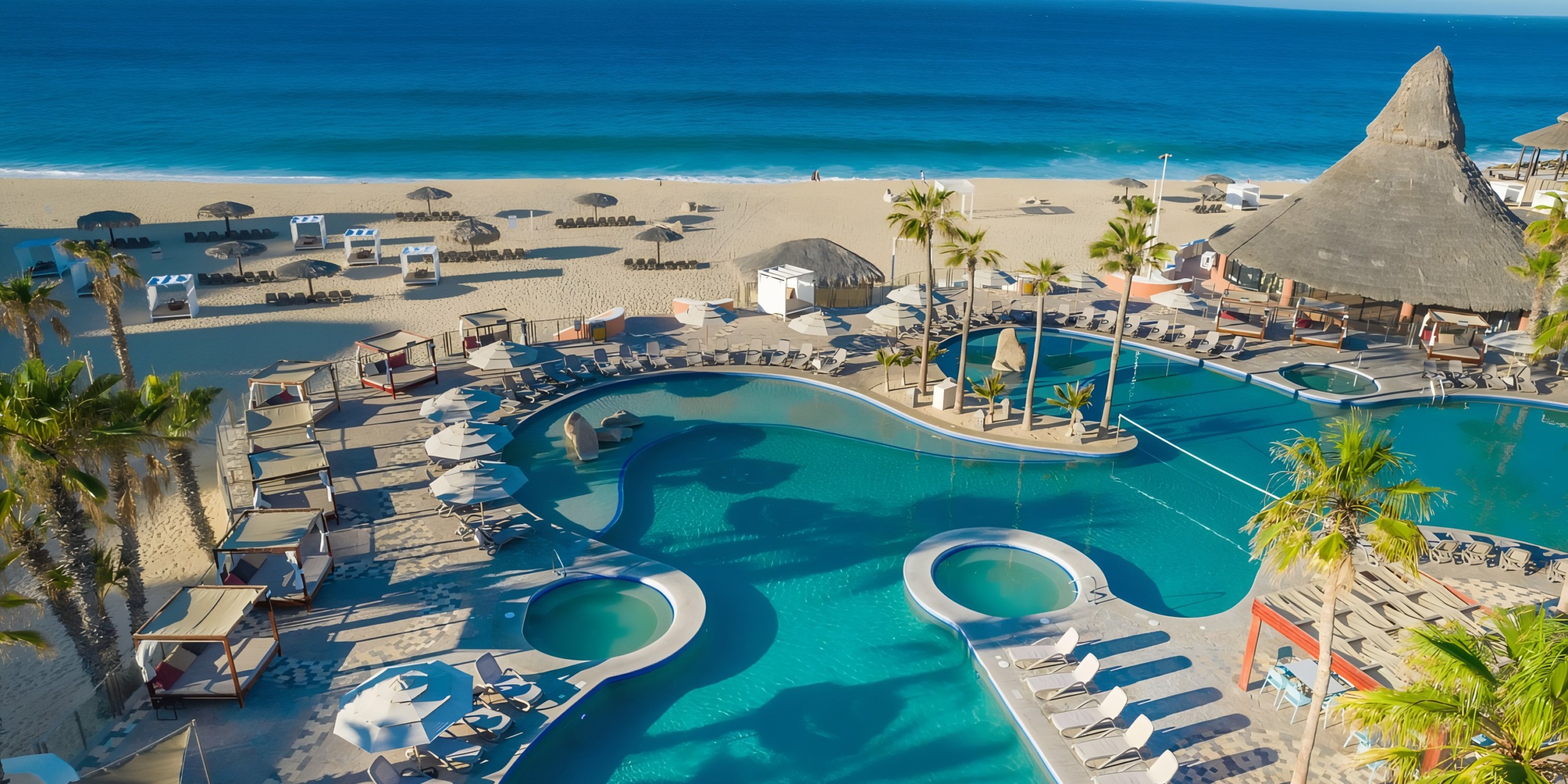 Aerial view of Sandos Finisterra Los Cabos resort with a swimming pool near a sandy beach.