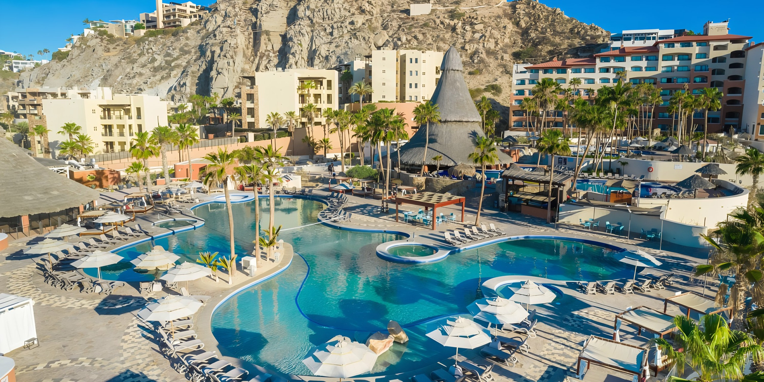 Sandos Finisterra Los Cabos with swimming pool and lounge chairs overlooking a scenic coastal landscape.