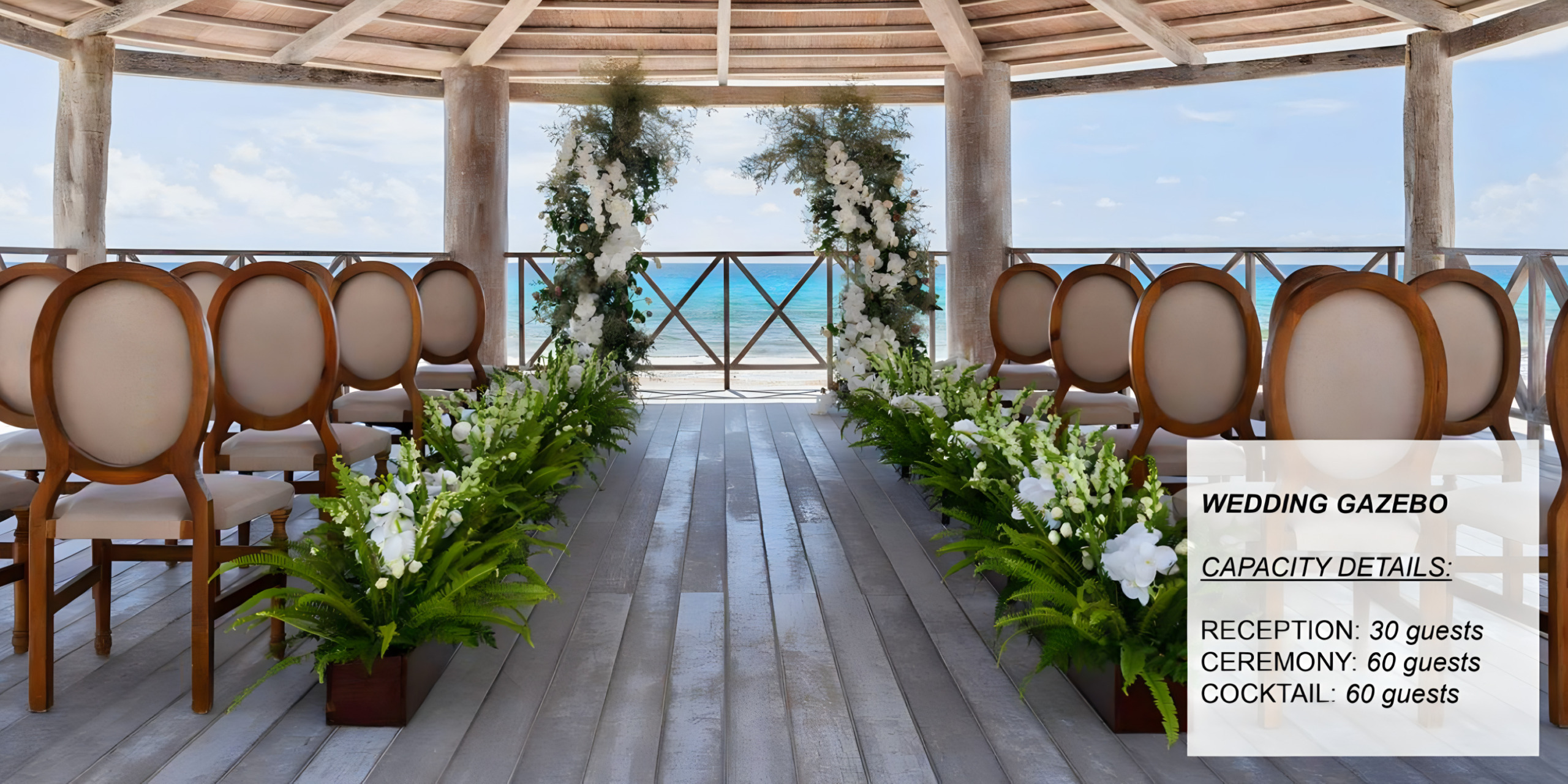 Destination wedding gazebo set for a ceremony, facing the sea, lined with rows of ceremony chairs and floral decorations, under a clear blue sky.