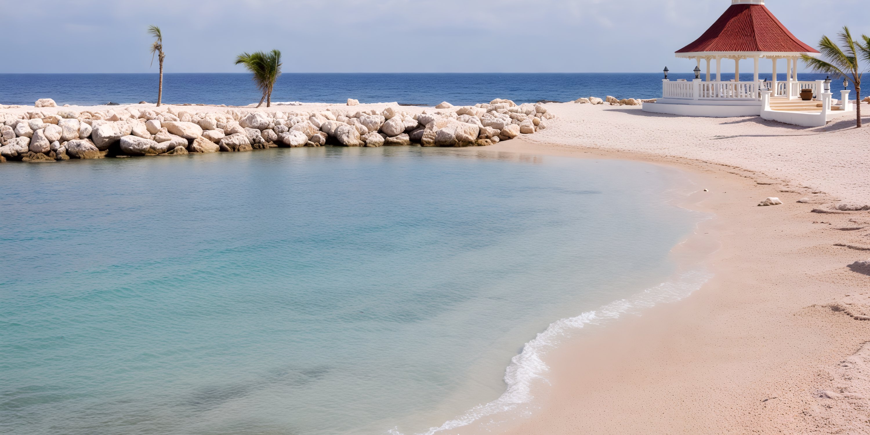 Bahia Principe Grand Jamaica offers an idyllic setting for a destination wedding, featuring a sandy beach adorned with a charming gazebo, swaying palm trees, and a picturesque rocky breakwater.