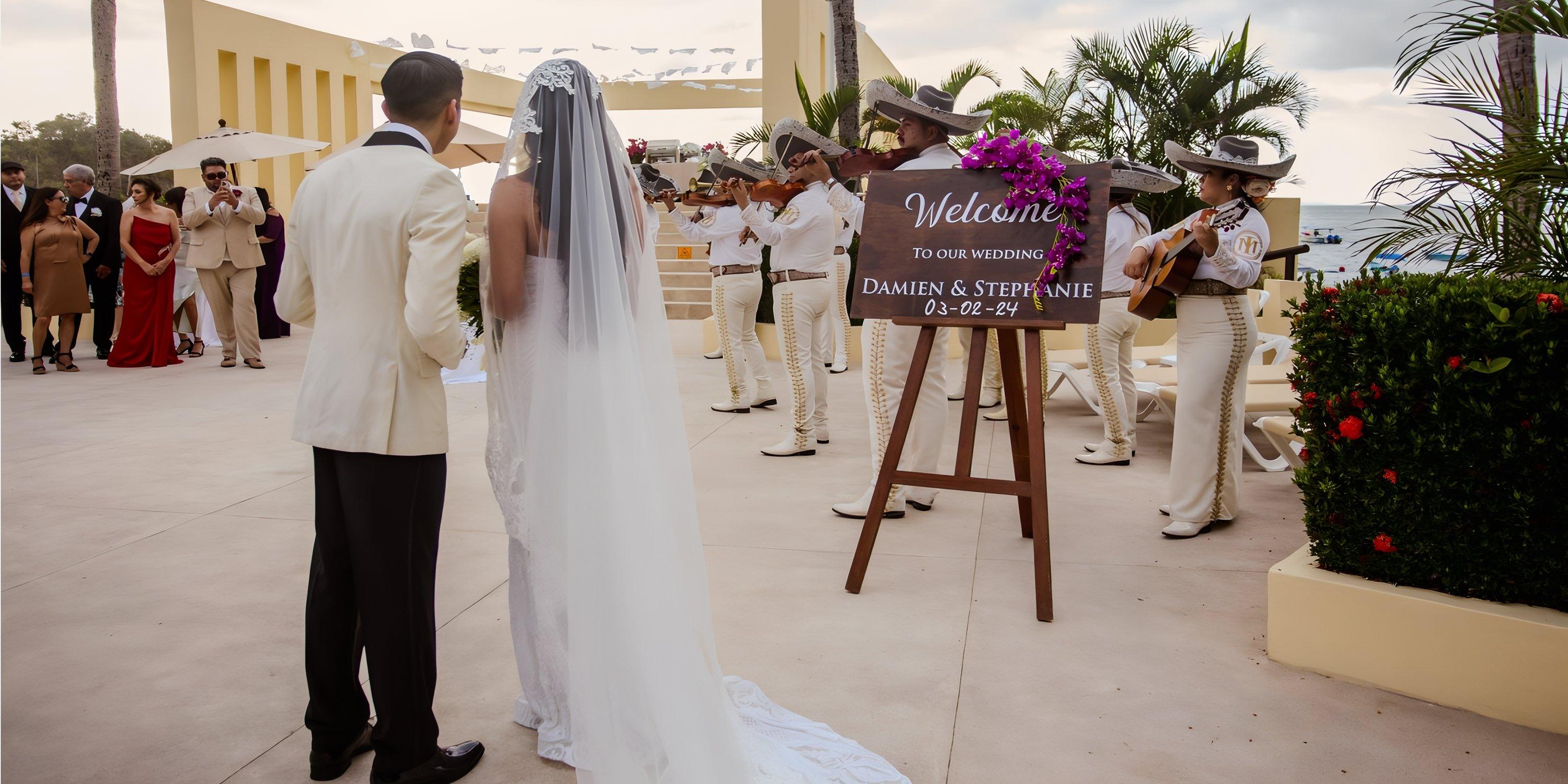 Bride and groom enjoy mariachi band at their destination wedding by a Barcelo Puerto Vallarta sign outdoors.