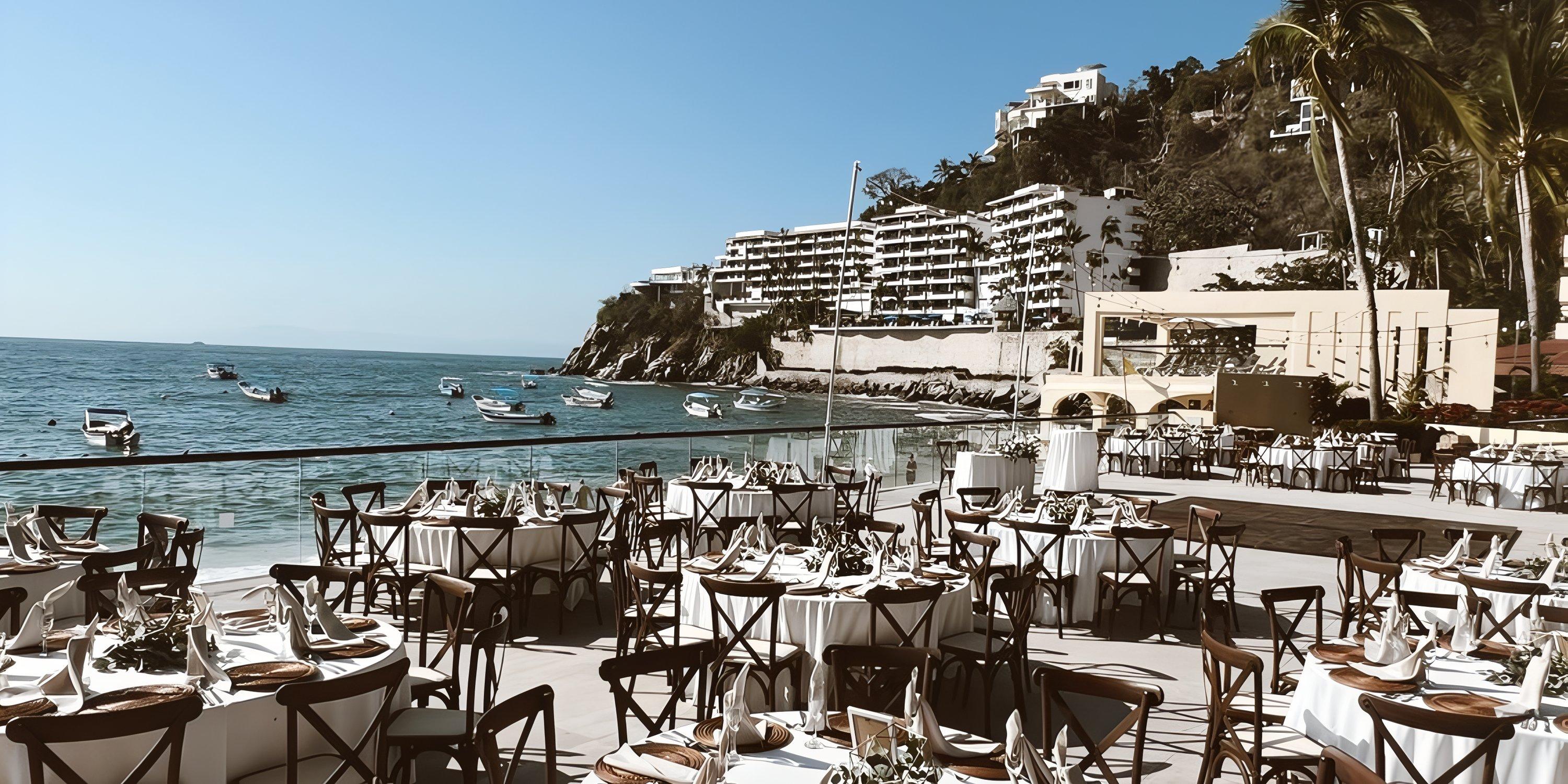 Outdoor dining setup for a destination wedding at Barcelo Puerto Vallarta, hillside buildings in view.