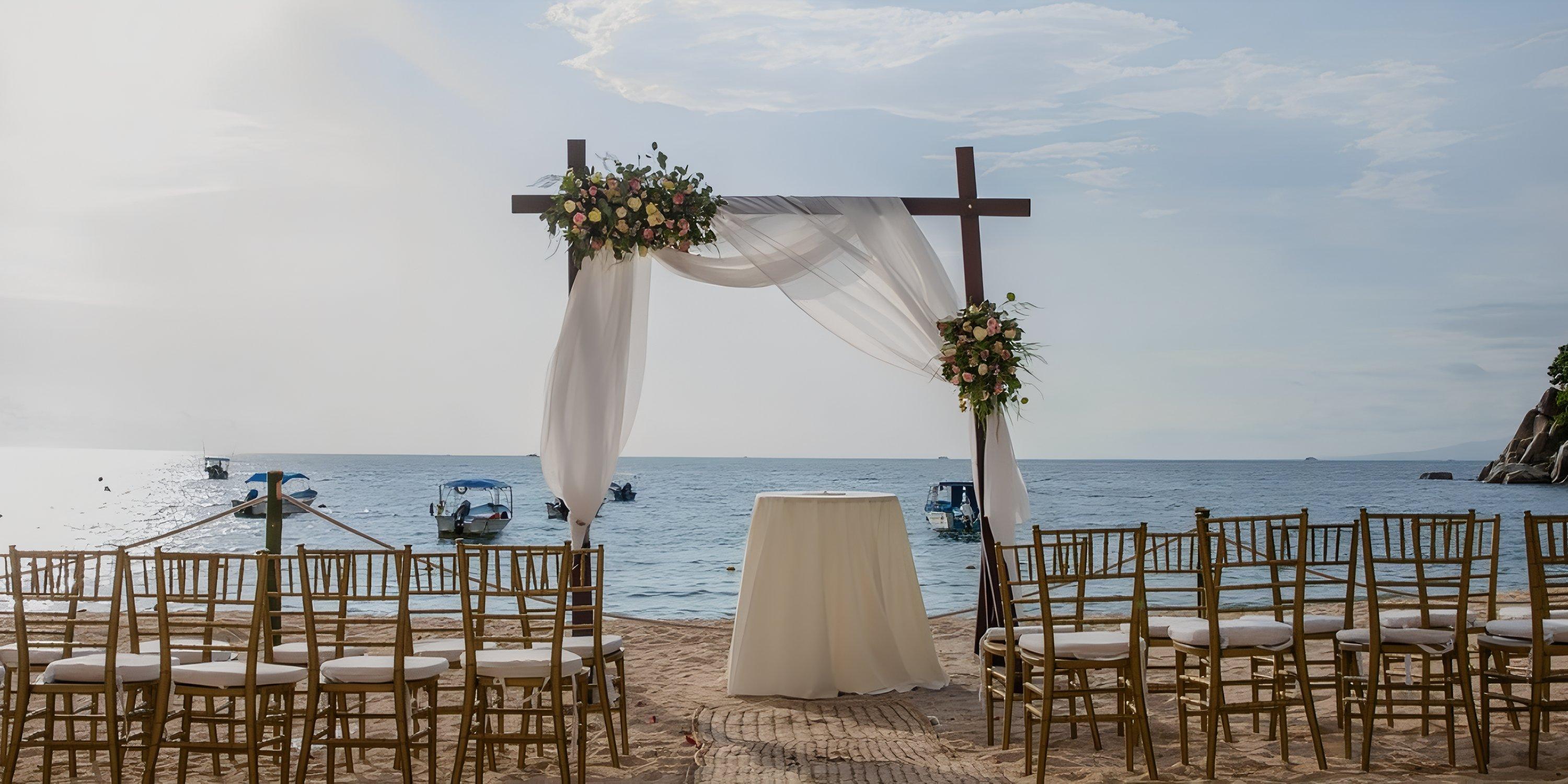Barcelo Puerto Vallarta destination wedding: chairs, floral arch, and altar set by the ocean.