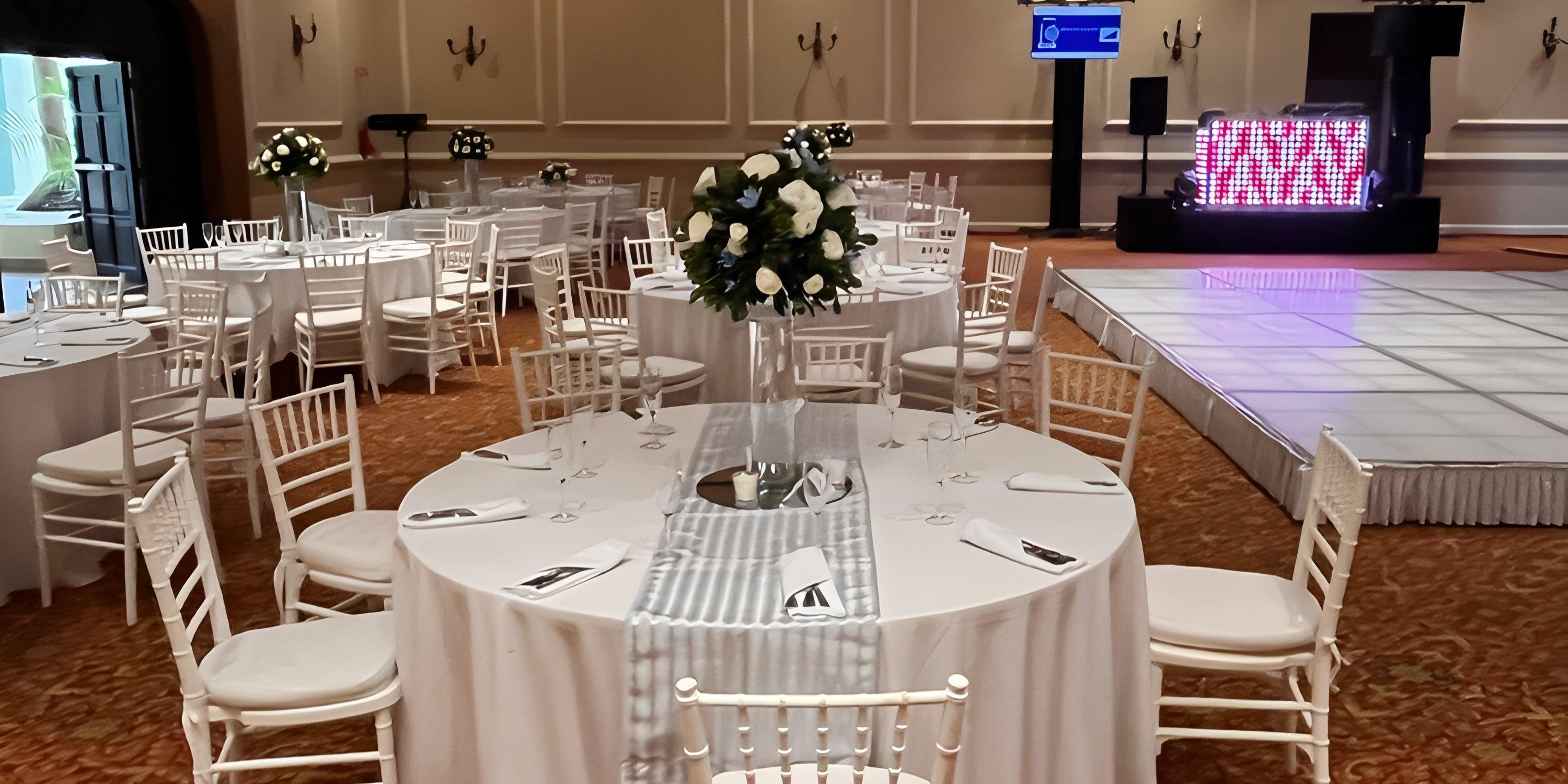 Barcelo Puerto Vallarta ballroom set for a destination wedding with round tables, white chairs, and a lit dance floor.
