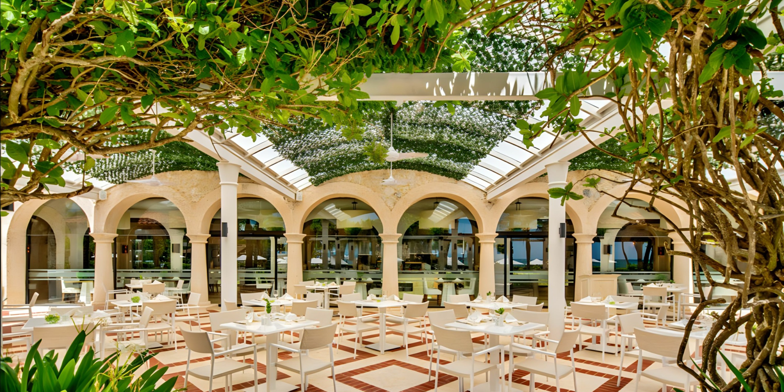 A wedding restaurant with white tables and chairs in the middle of a garden.