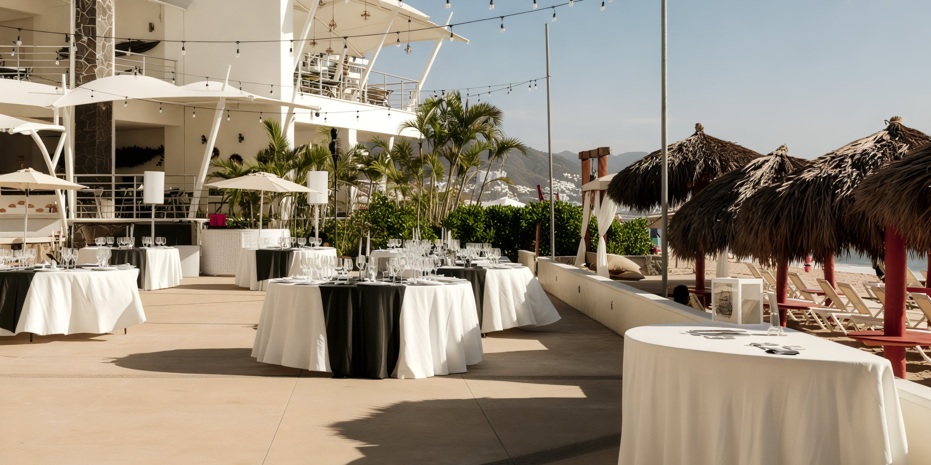 Outdoor dining at Dreams Vallarta Bay offers an idyllic setting for a destination wedding, featuring round tables adorned with white cloths and a stunning beach view.