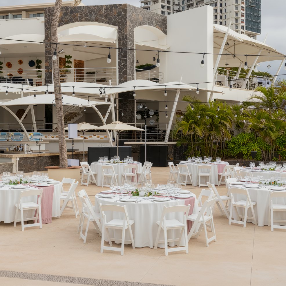 Experience the enchanting setting of a Dreams Vallarta Bay destination wedding, complete with round tables adorned with elegant white cloths and twinkling string lights.