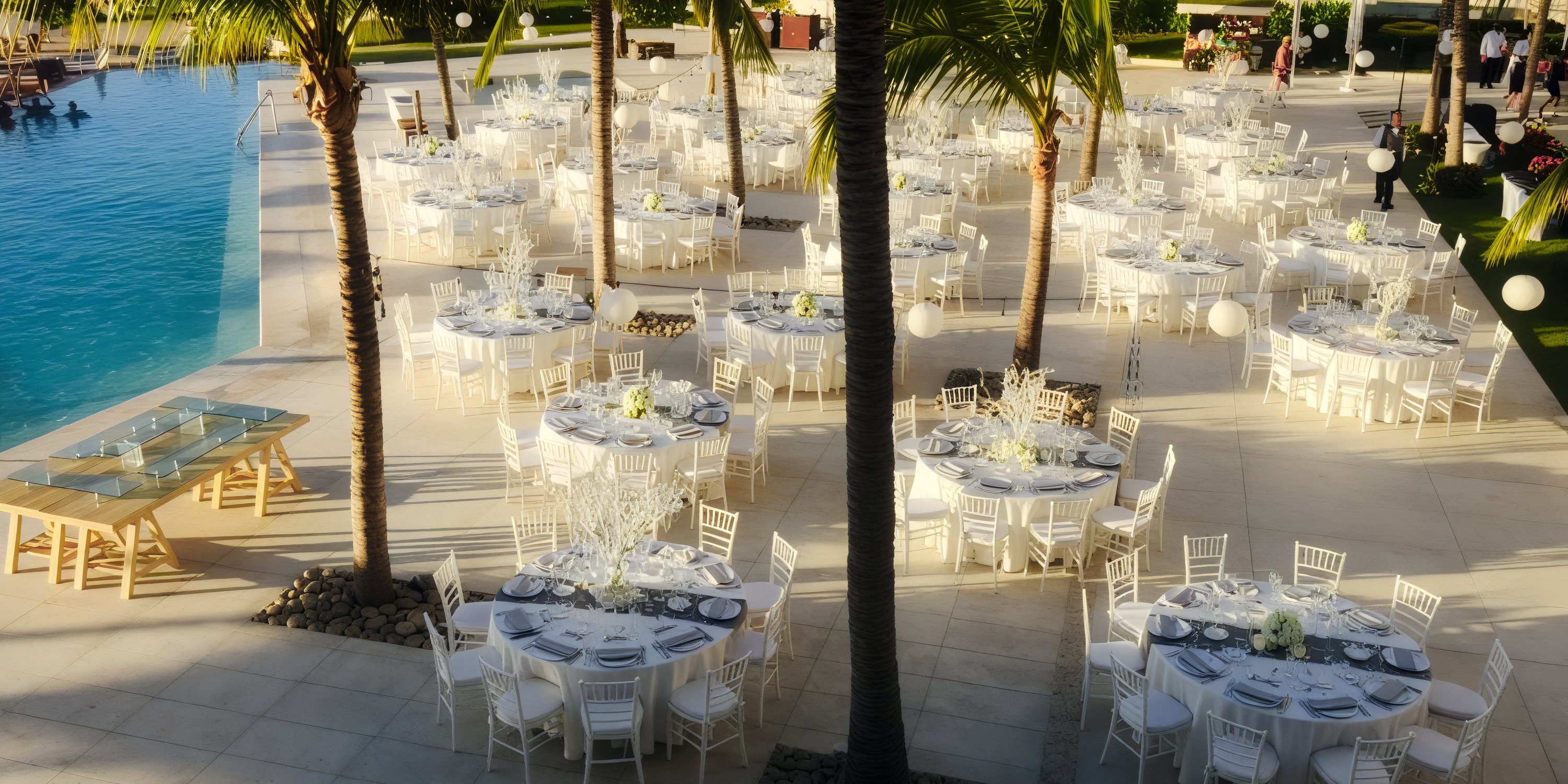 A stunning destination wedding setup by the pool at Dreams Vallarta Bay, featuring elegant round tables and chic white chairs.