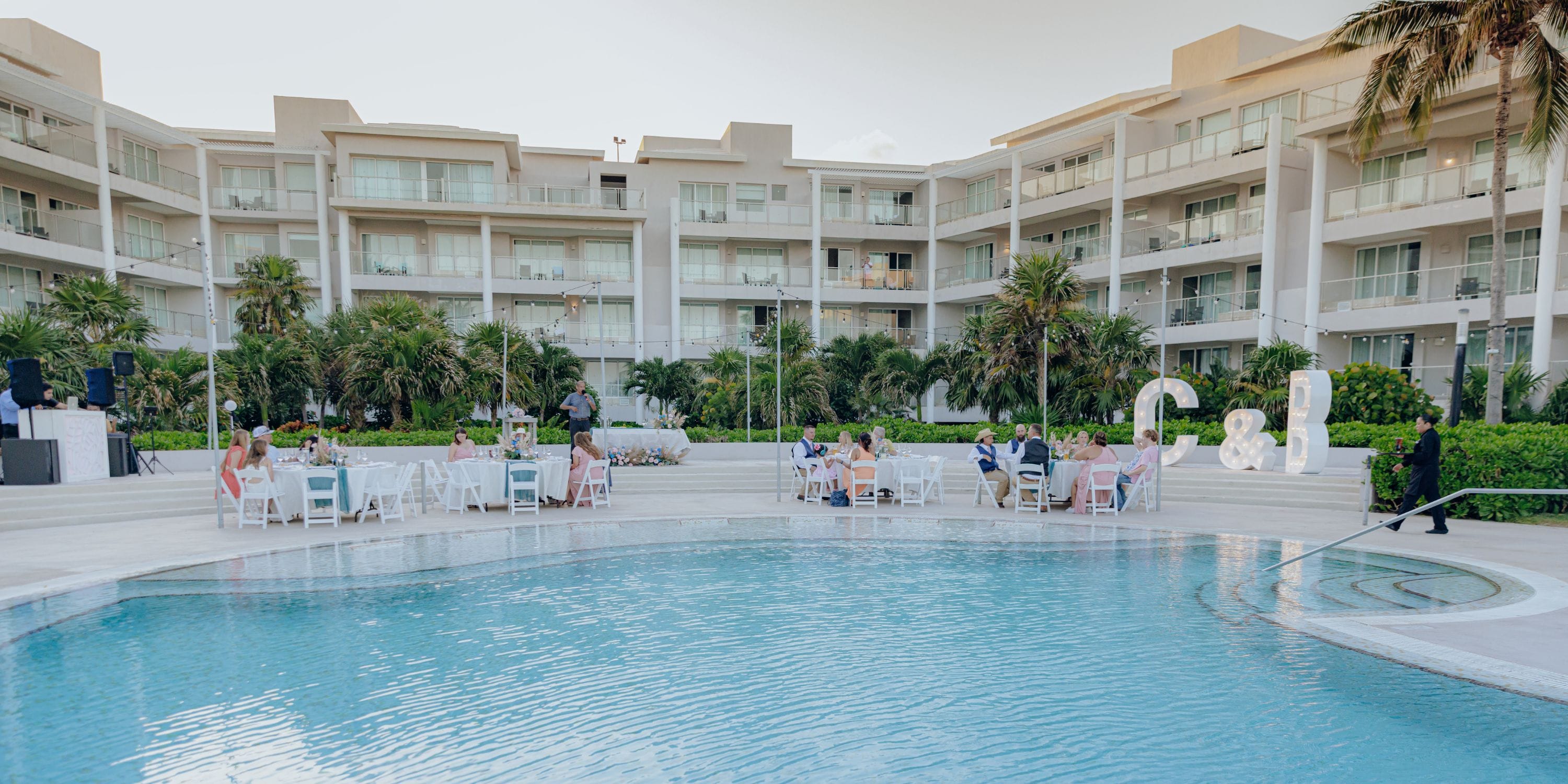 Guests gathered at tables by the pool for a destination wedding at Dreams Jade Riviera Cancun.