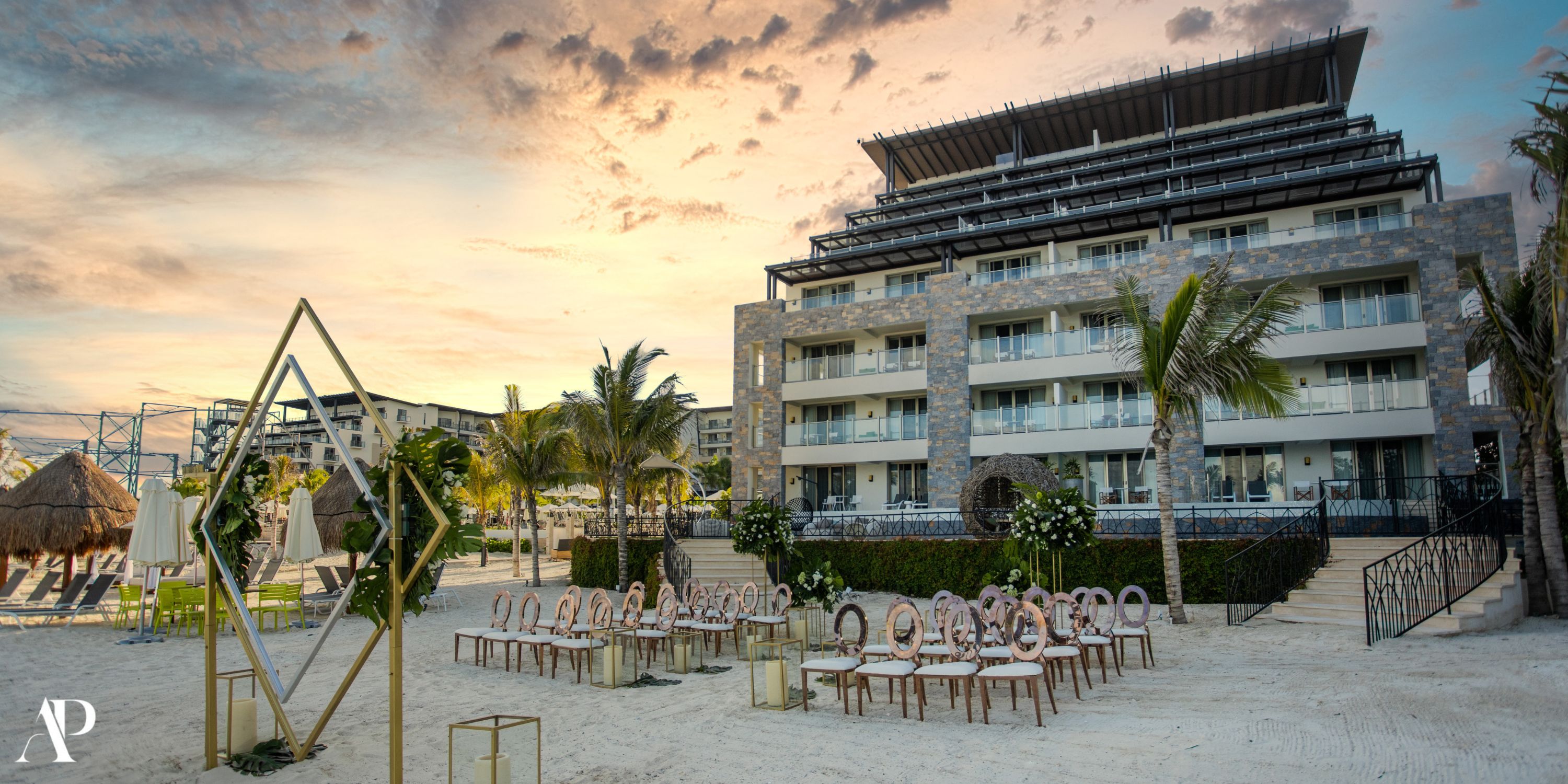 Destination wedding ceremony setup with elegant chairs and décor on the beach at Dreams Natura at sunset.
