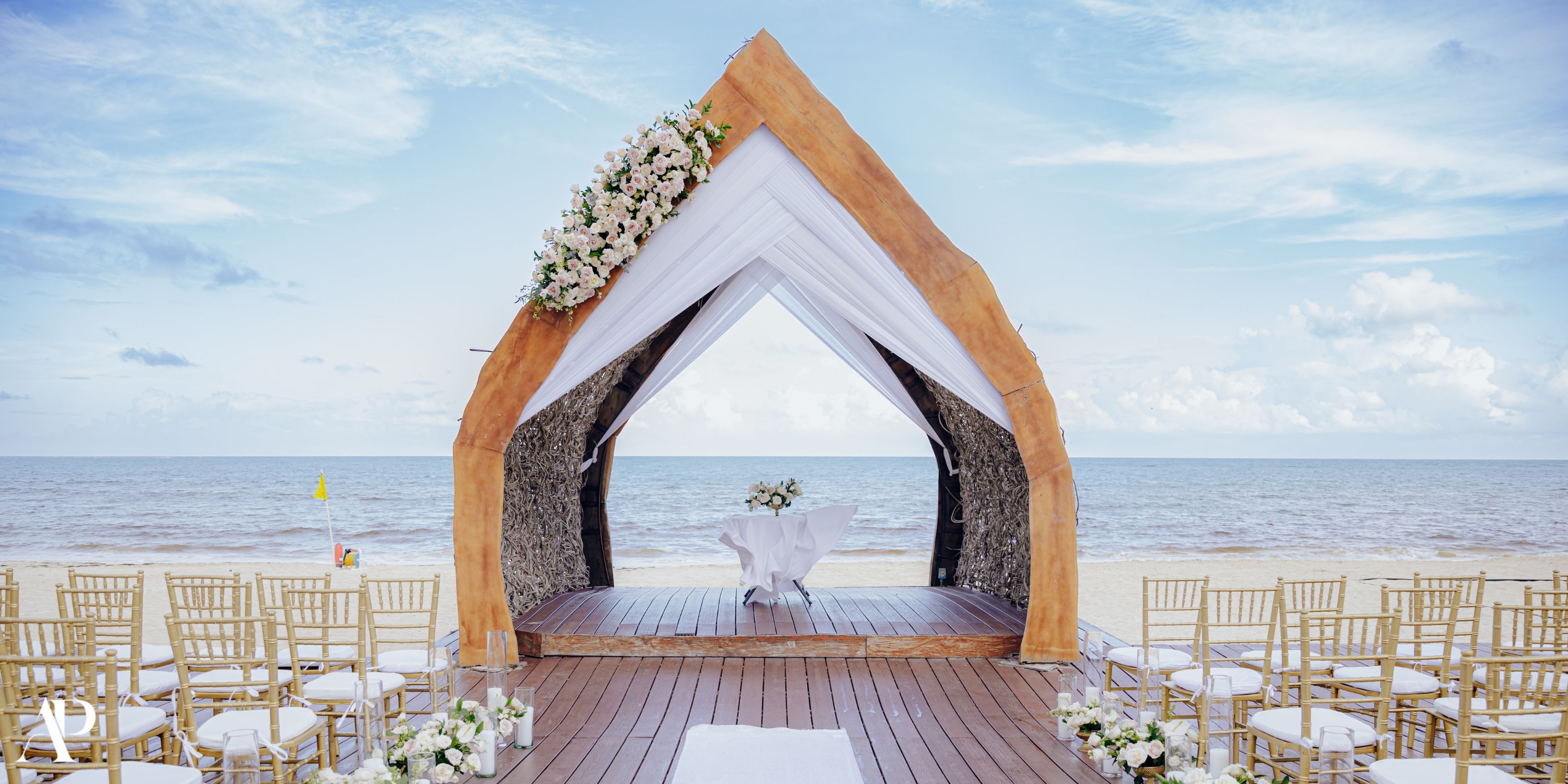 Wooden arch and chairs set up on the sand for a Dreams Natura destination wedding by the ocean.