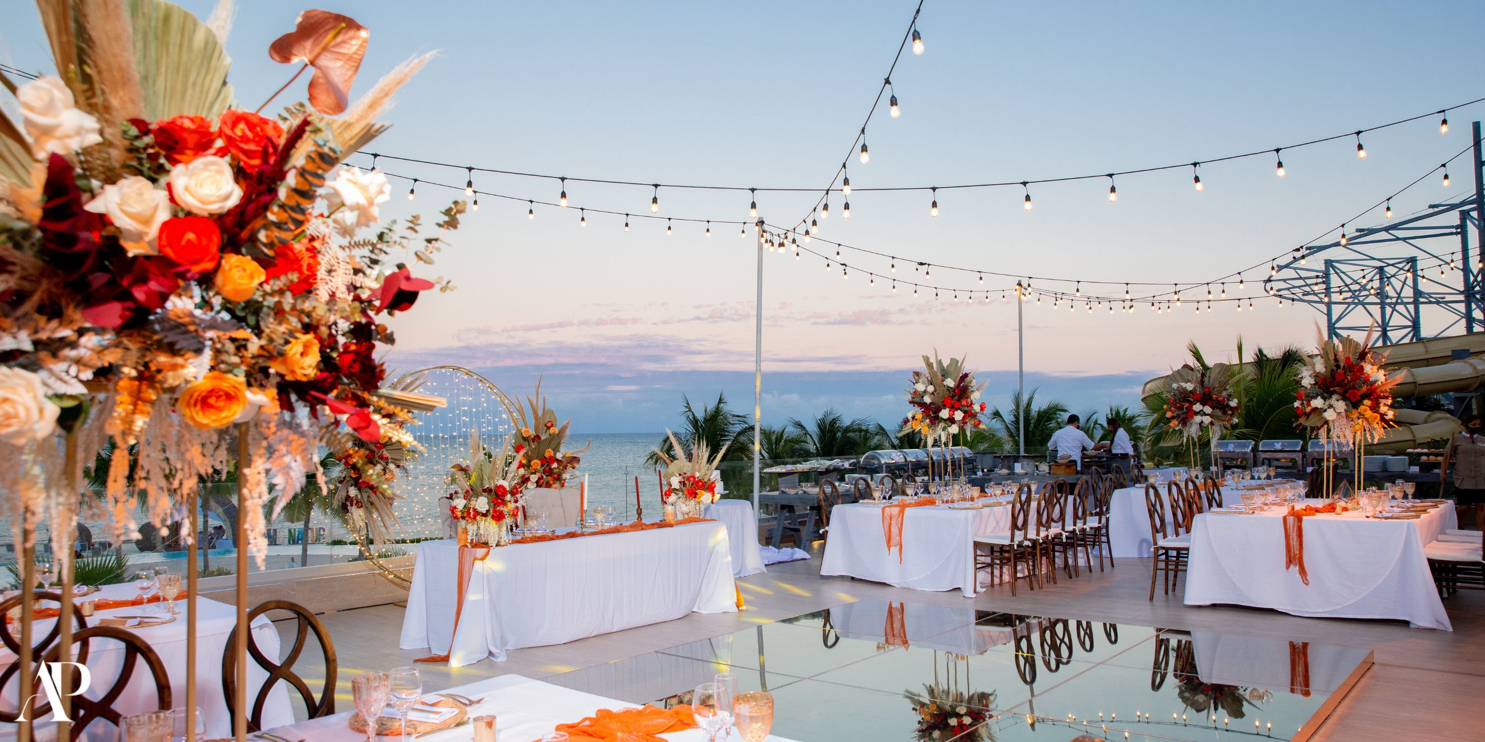 Destination wedding at Dreams Natura: elegant decorated tables, string lights, and sunset ocean views.