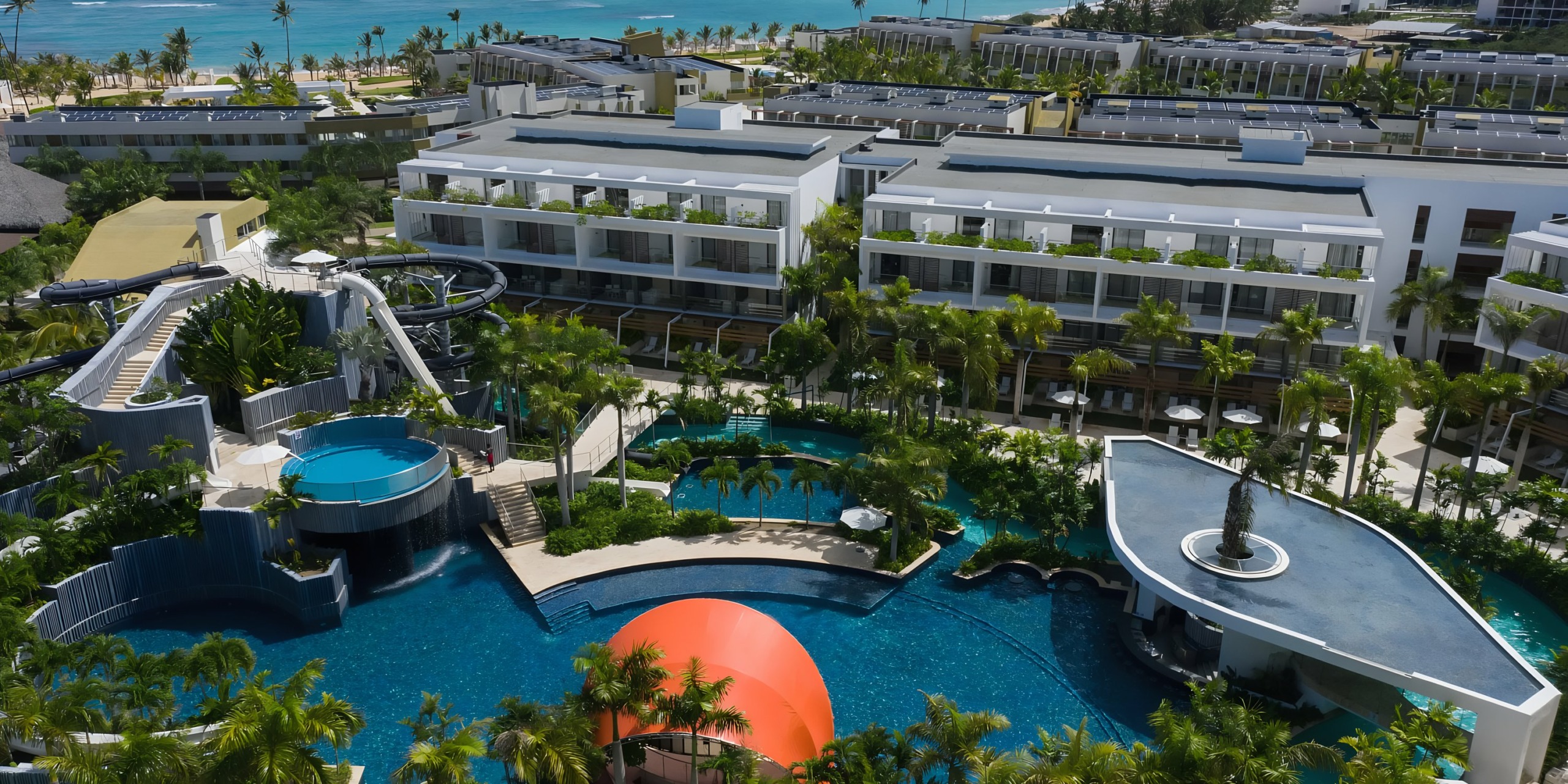 Aerial view of Dreams Onyx resort with swimming pools, water slides, and ocean in the background.