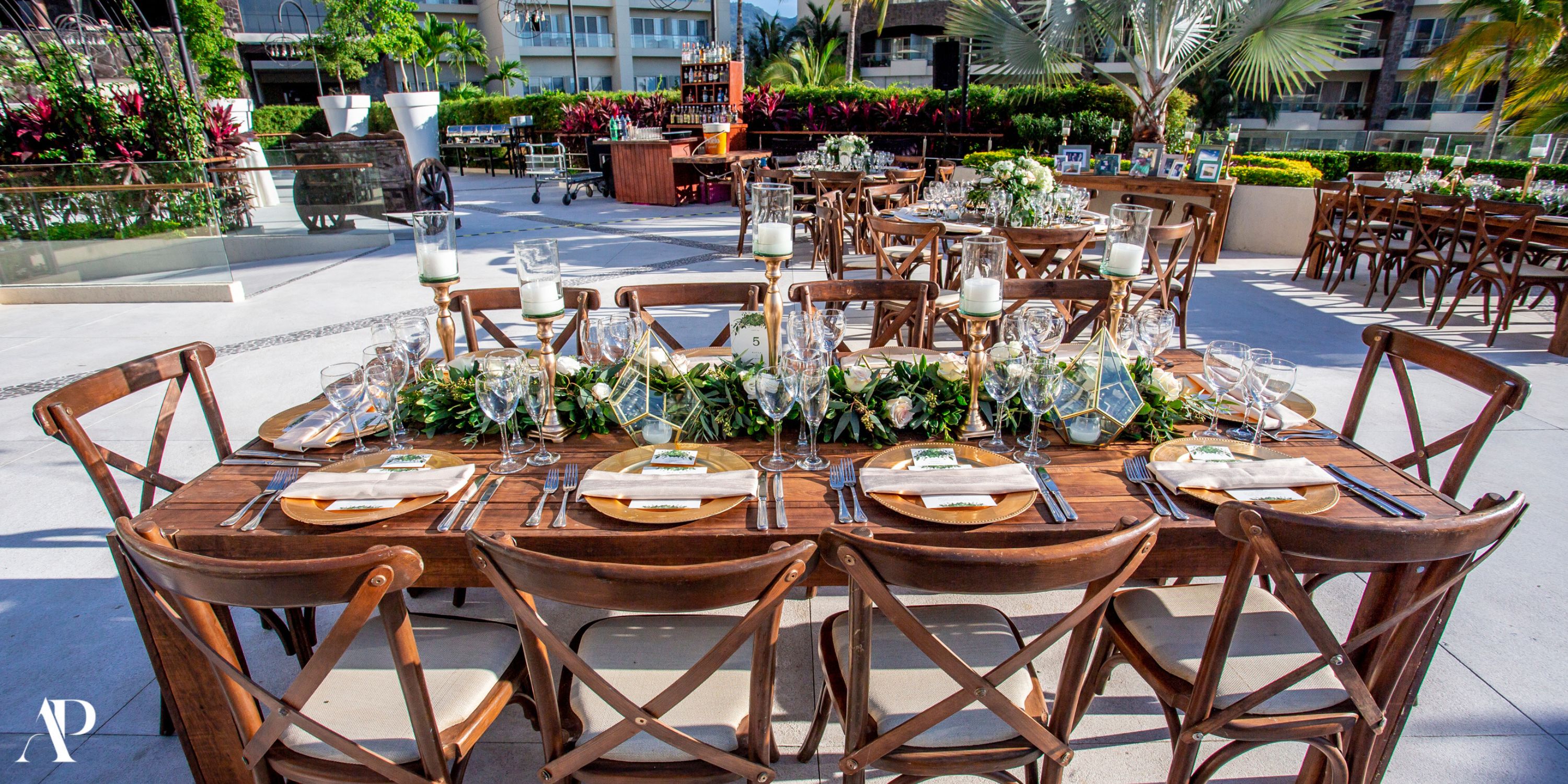 Outdoor wedding dining setup for eight at Dreams Vallarta Bay, with glassware, candles, and greenery.