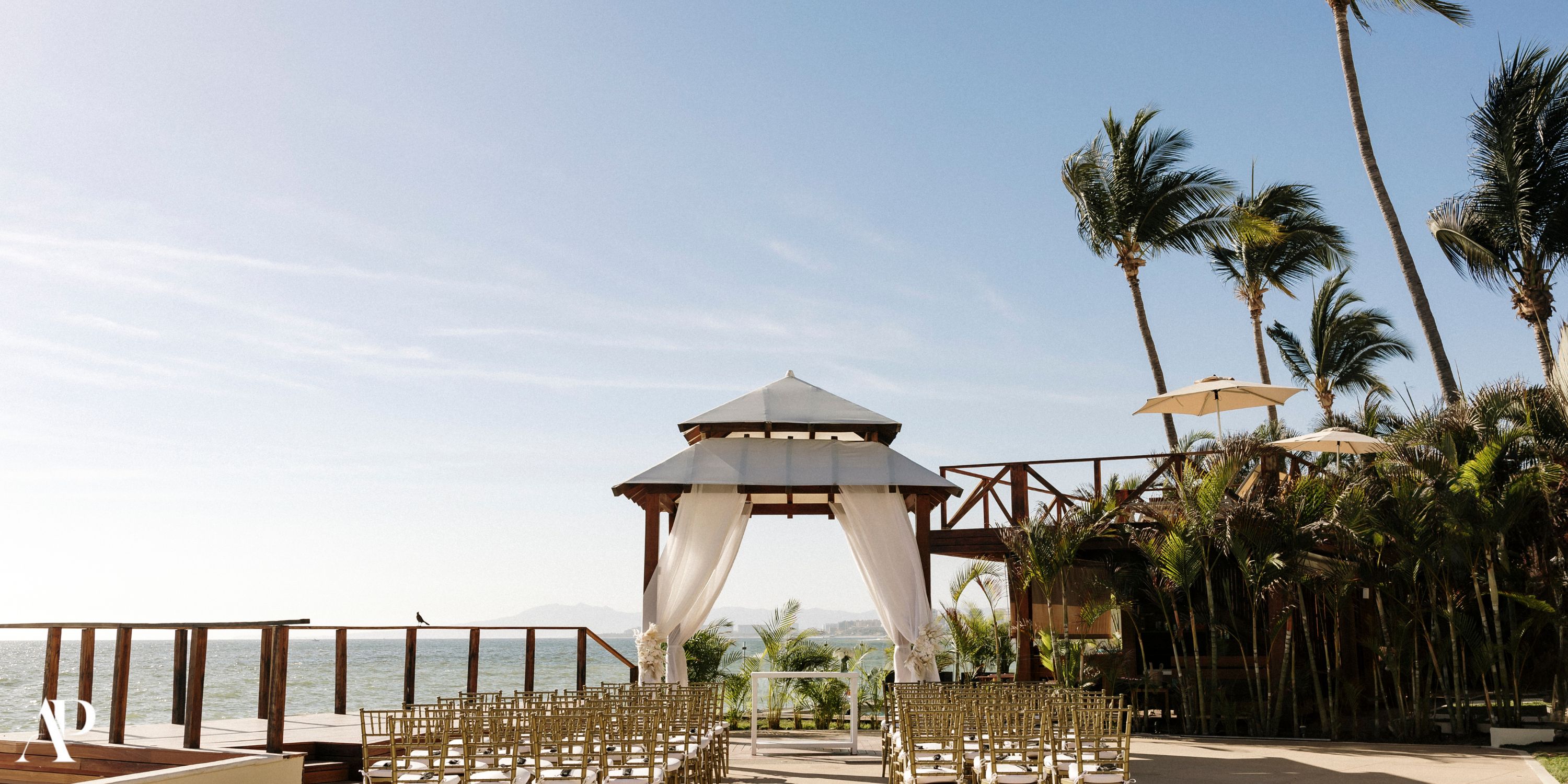 Dreams Vallarta Bay features a scenic destination wedding setup with chairs facing a white-draped gazebo.