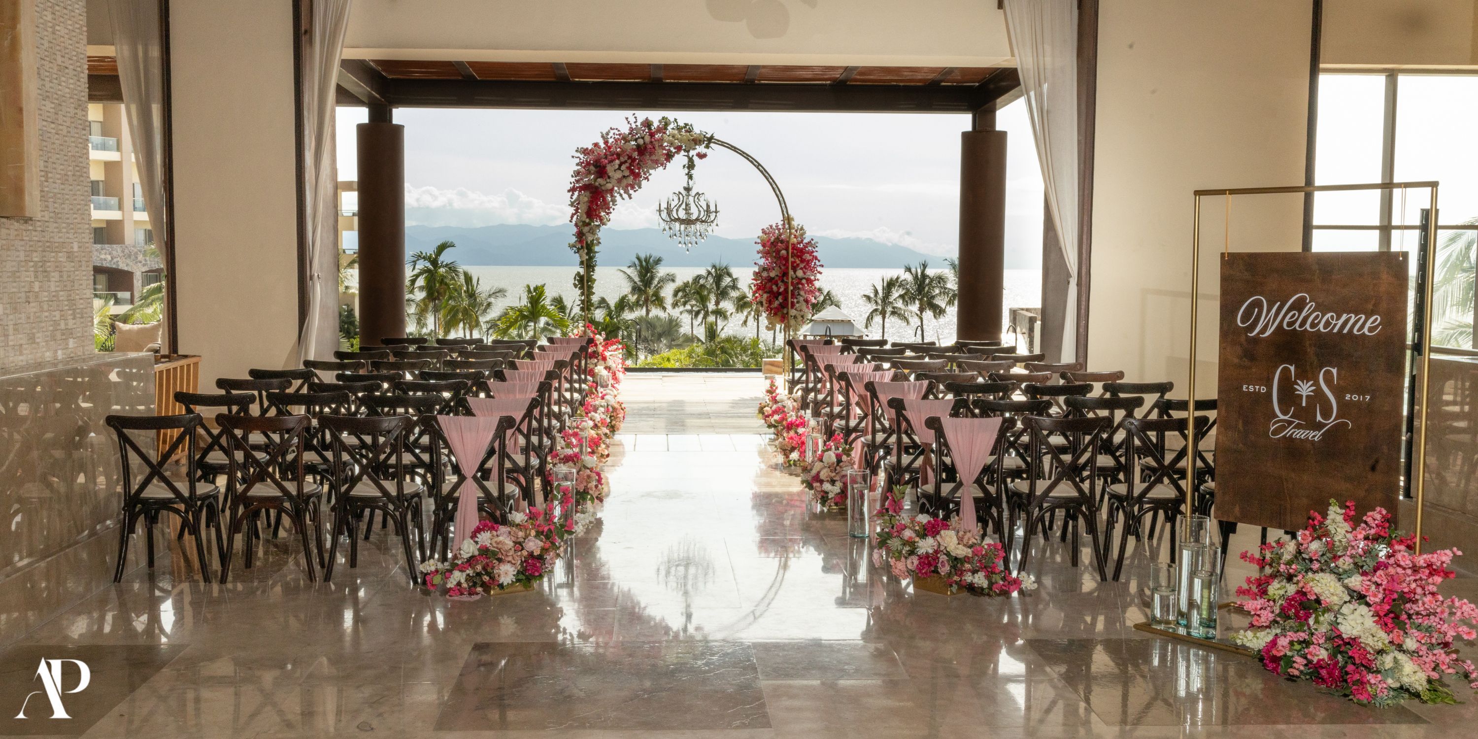 Destination wedding at Dreams Vallarta Bay with elegant pink florals and a chic welcome sign indoors.