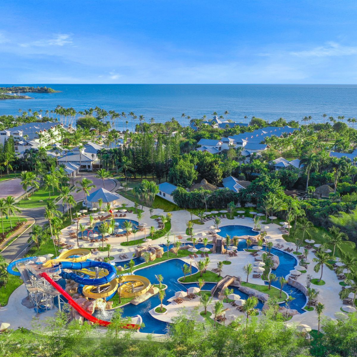 Aerial view of Dreams La Romana Resort, a destination wedding spot with pools, slides, palms, and ocean.