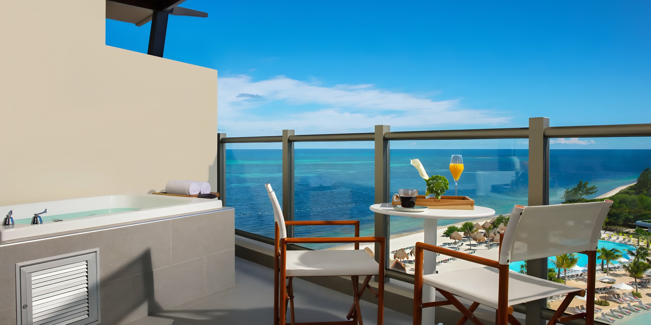 A Dreams Natura with a hot tub overlooking a tropical beach and ocean, complete with a table set for two.