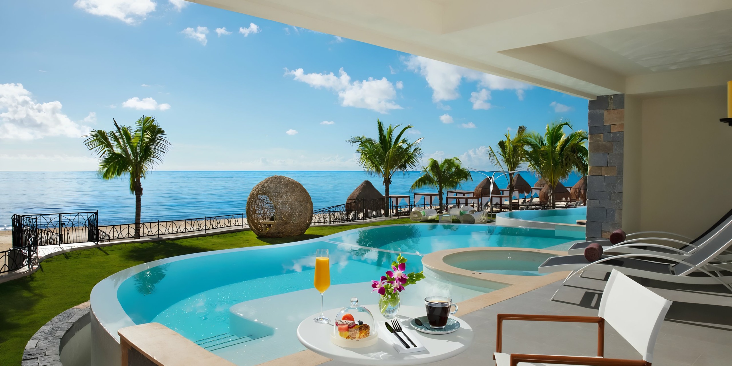 Dreams Natura seaside resort balcony with breakfast overlooking an infinity pool and ocean.