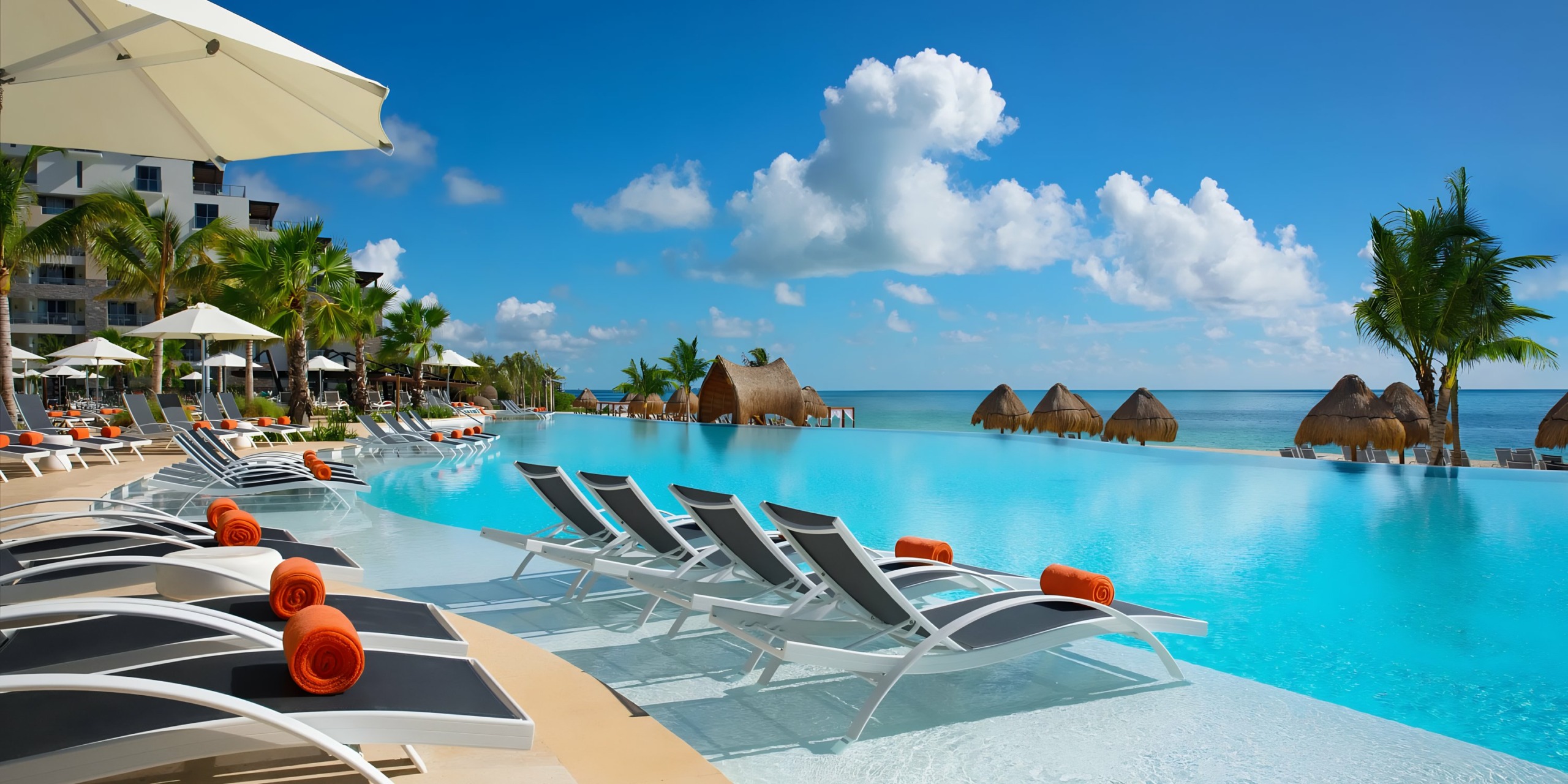 Dreams Natura resort swimming pool with lounge chairs and ocean view.