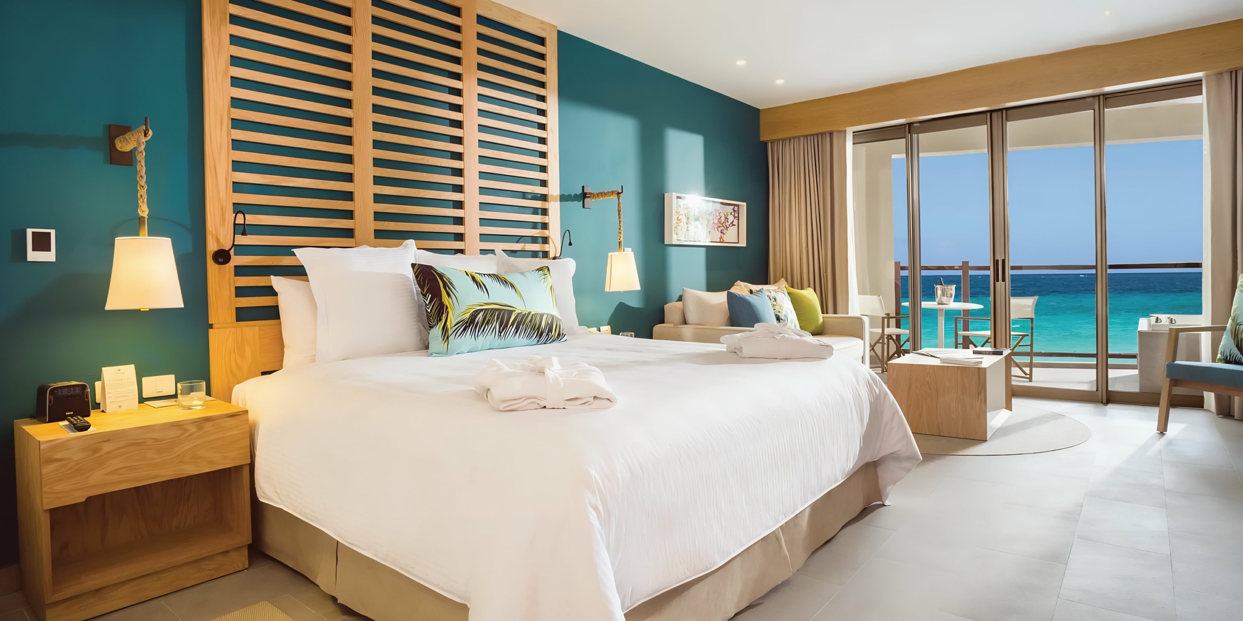 A bright and modern Dreams Natura hotel room with a large bed facing a balcony overlooking the ocean.