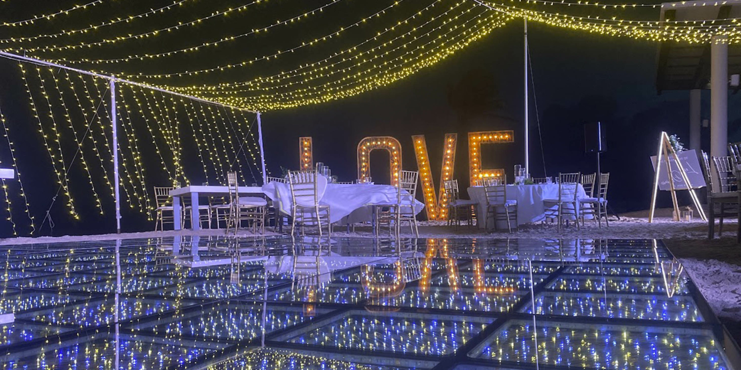A wedding reception at the Breathless Riviera Cancún Resort & Spa with a lit up love sign on a glass floor.