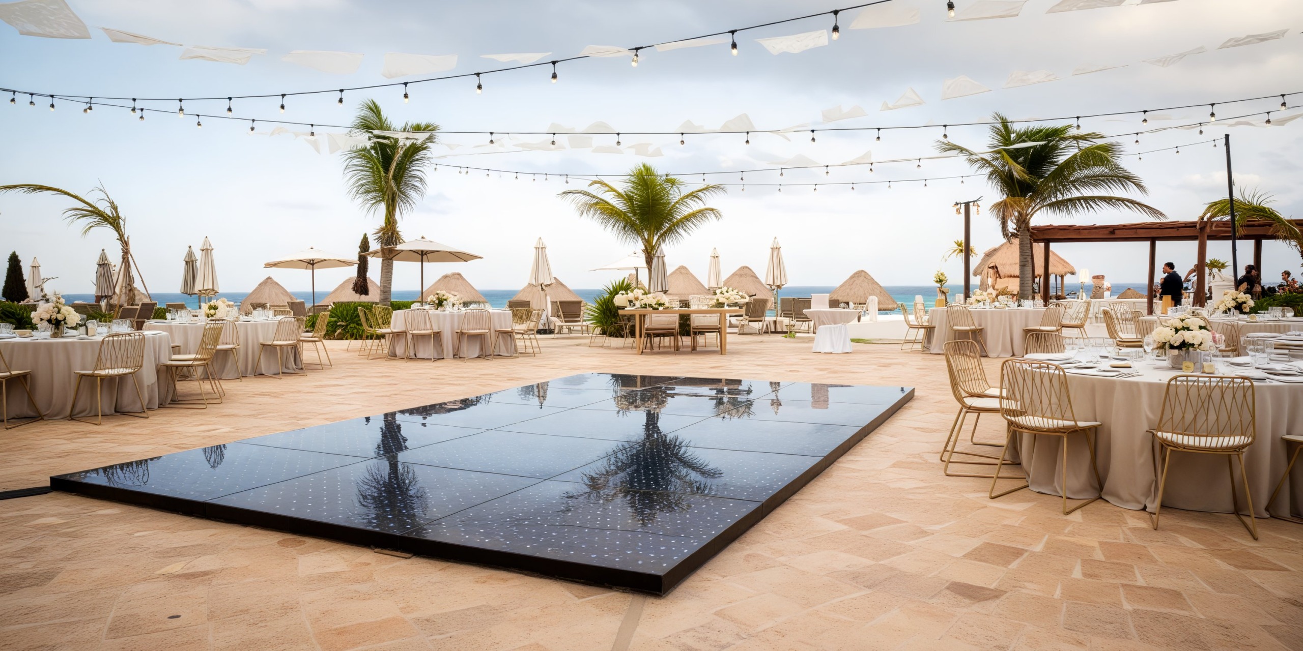Destination wedding at Fiesta Americana Condesa Cancun: set amidst towering palm trees and overlooking the beach, with elegantly arranged tables, chairs, and twinkling lights.