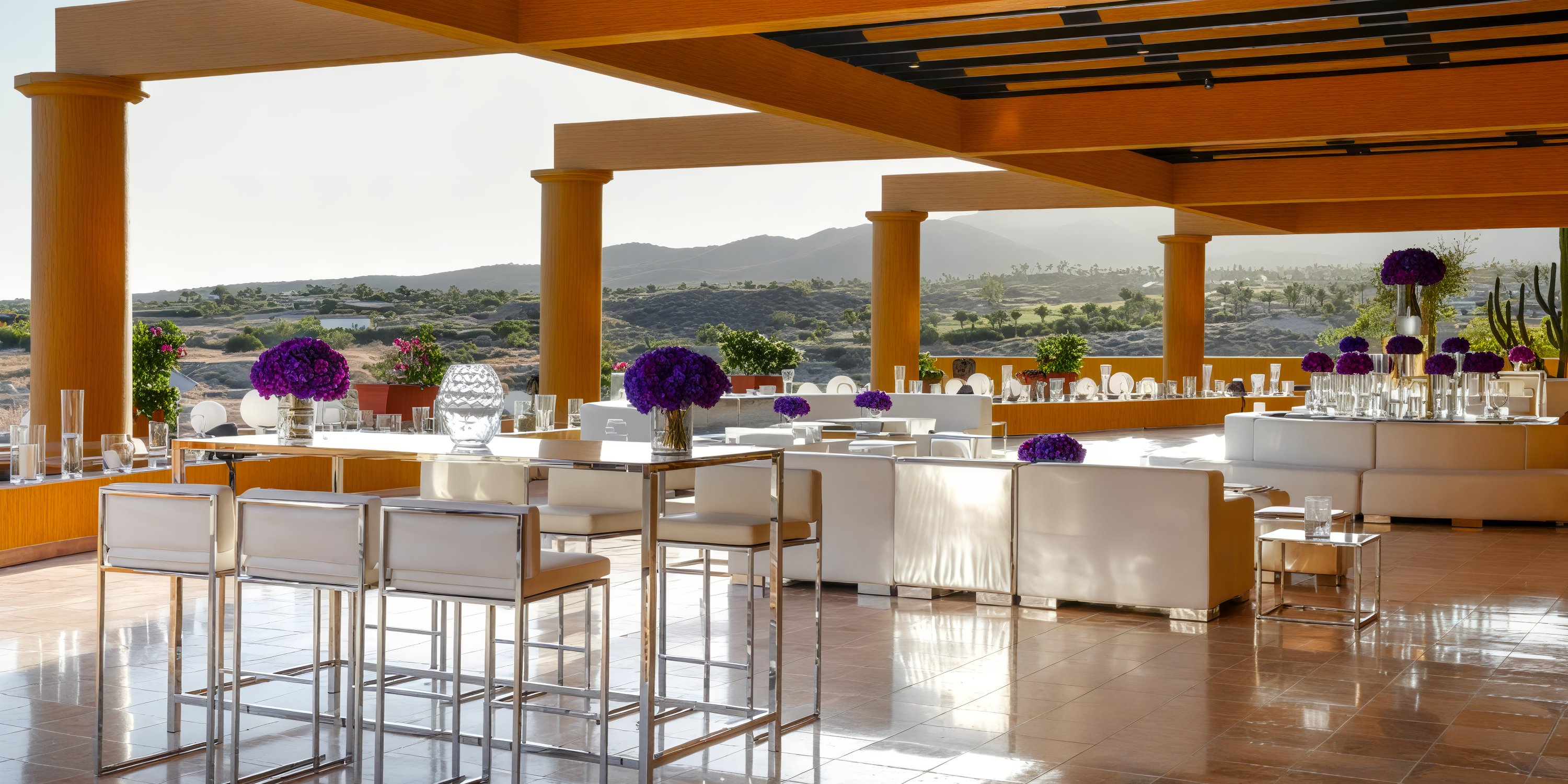An outdoor terrace perfect for a destination wedding, featuring white furniture adorned with purple floral decor and breathtaking views of the mountains.