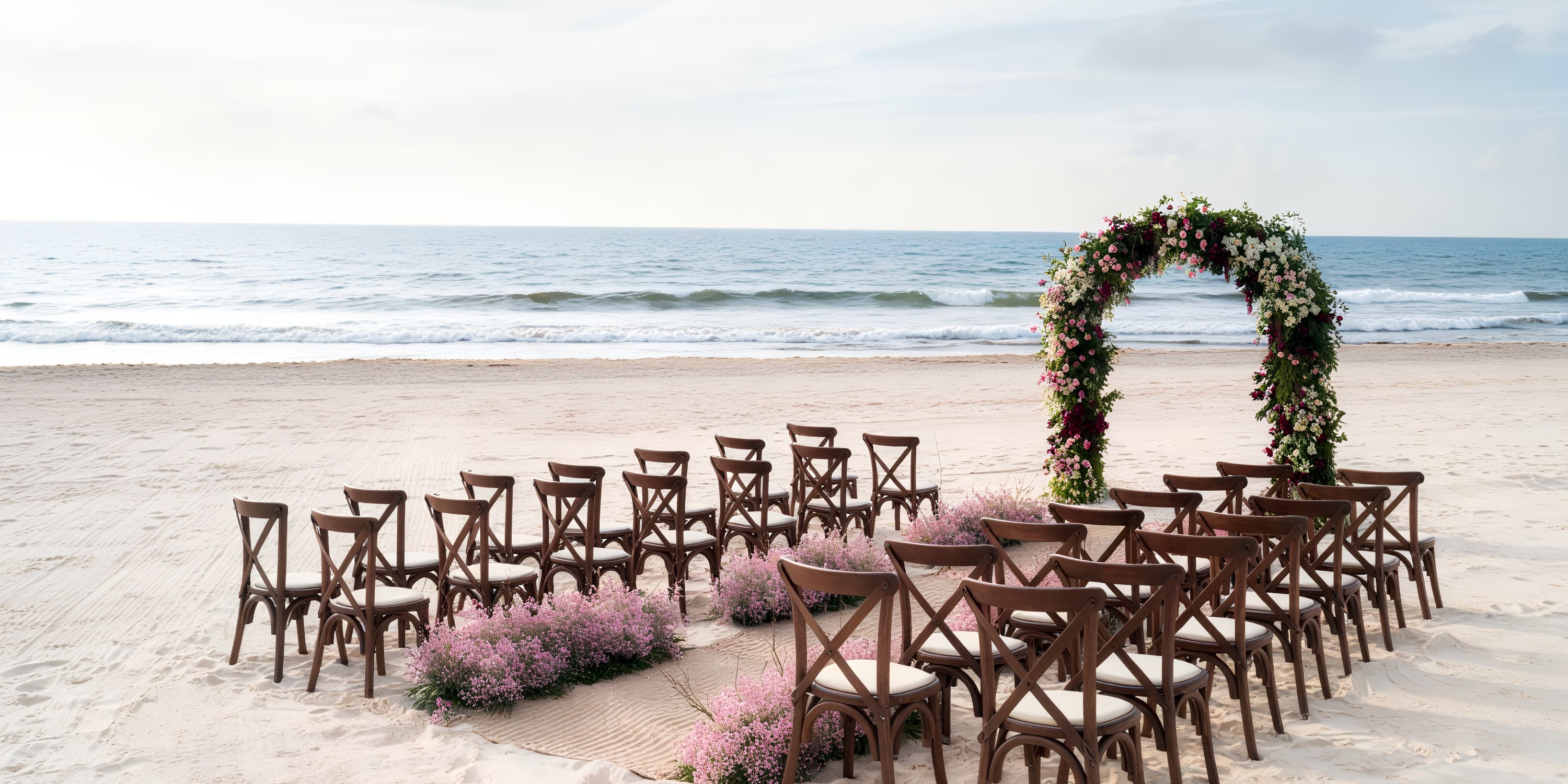 Hyatt Zilara Cancun: Destination wedding featuring a floral arch and wooden chairs set against the backdrop of the sea.