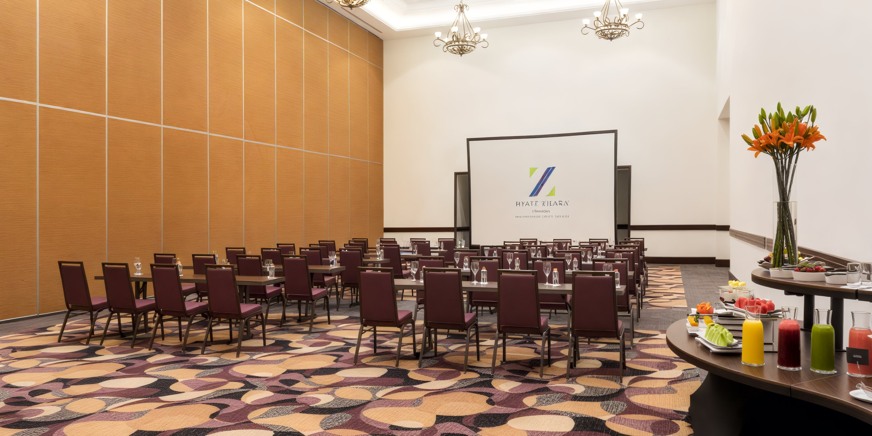 Hyatt Zilara Cancun's conference room, adorned with chairs, a screen, tables, drinks, and flowers, offers an ideal setting for a destination wedding.