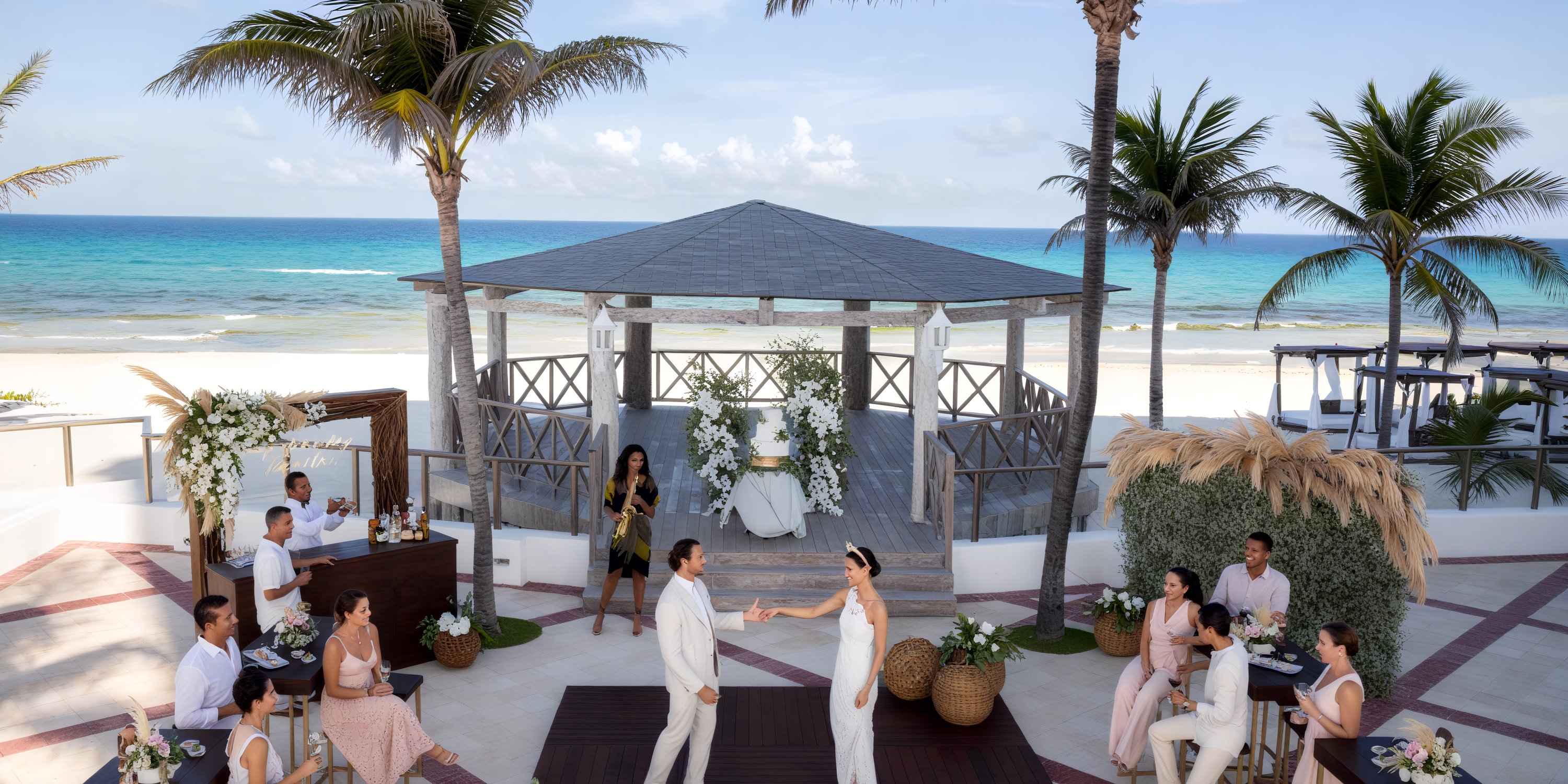 A couple dancing outdoors at the Hyatt Zilara Cancun beach gazebo during their destination wedding, with guests watching.