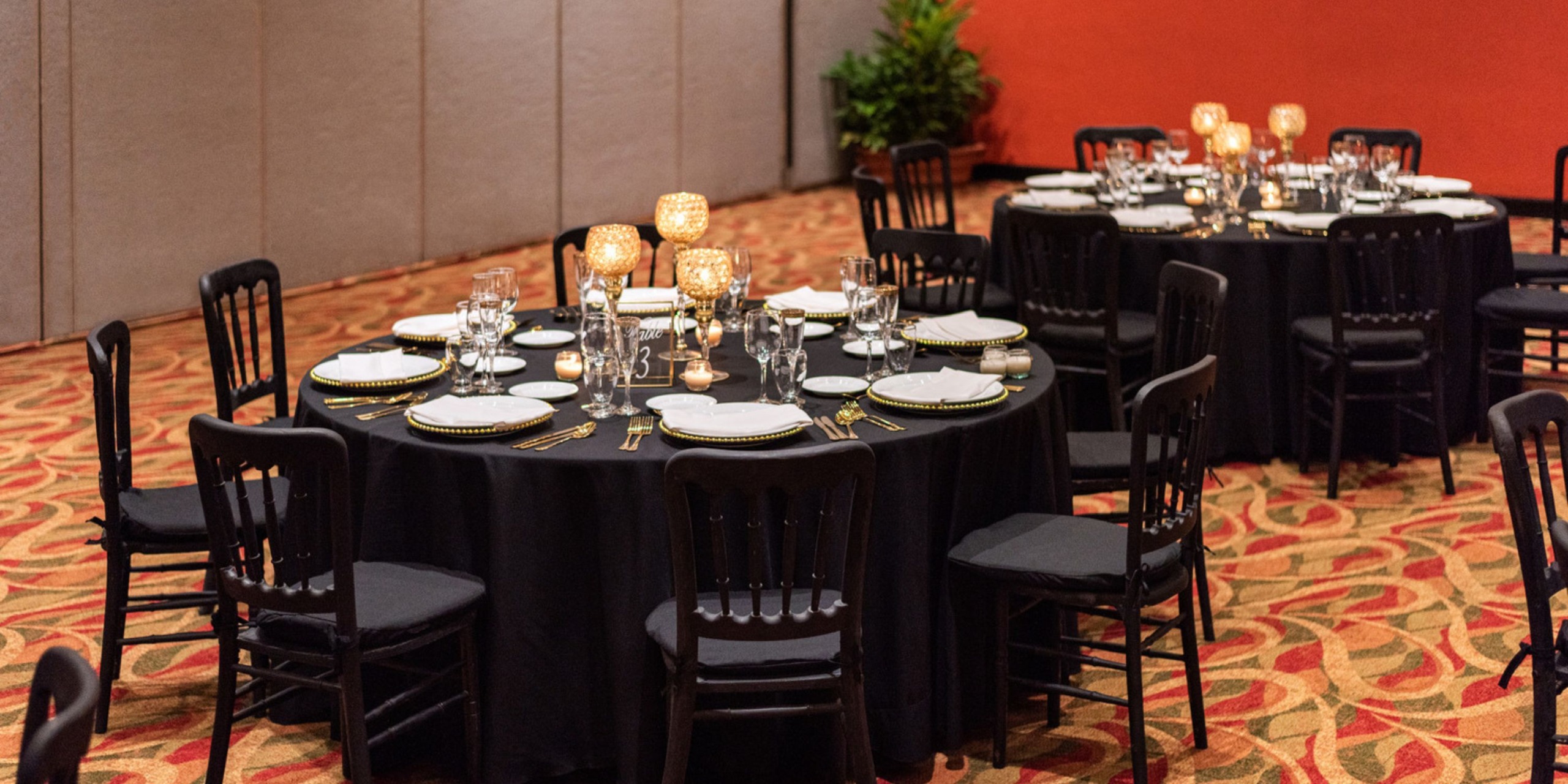 At Hyatt Ziva Puerto Vallarta, the elegantly set dining tables, adorned with black tablecloths atop plush carpeting, offer a sophisticated ambiance perfect for a destination wedding.
