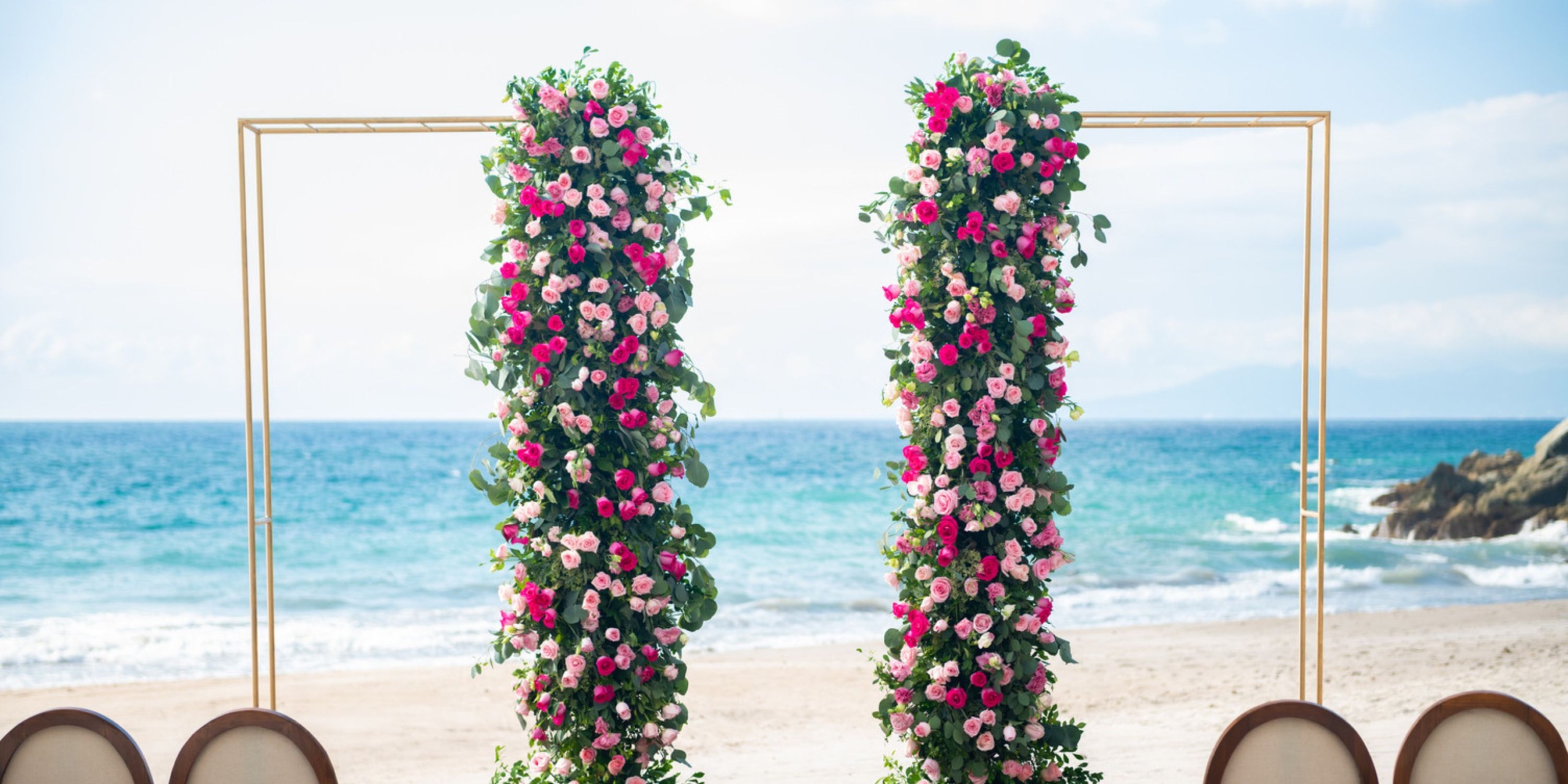 Hyatt Ziva Puerto Vallarta offers a stunning beach arch adorned with pink flowers and lush greenery, perfect for a destination wedding.