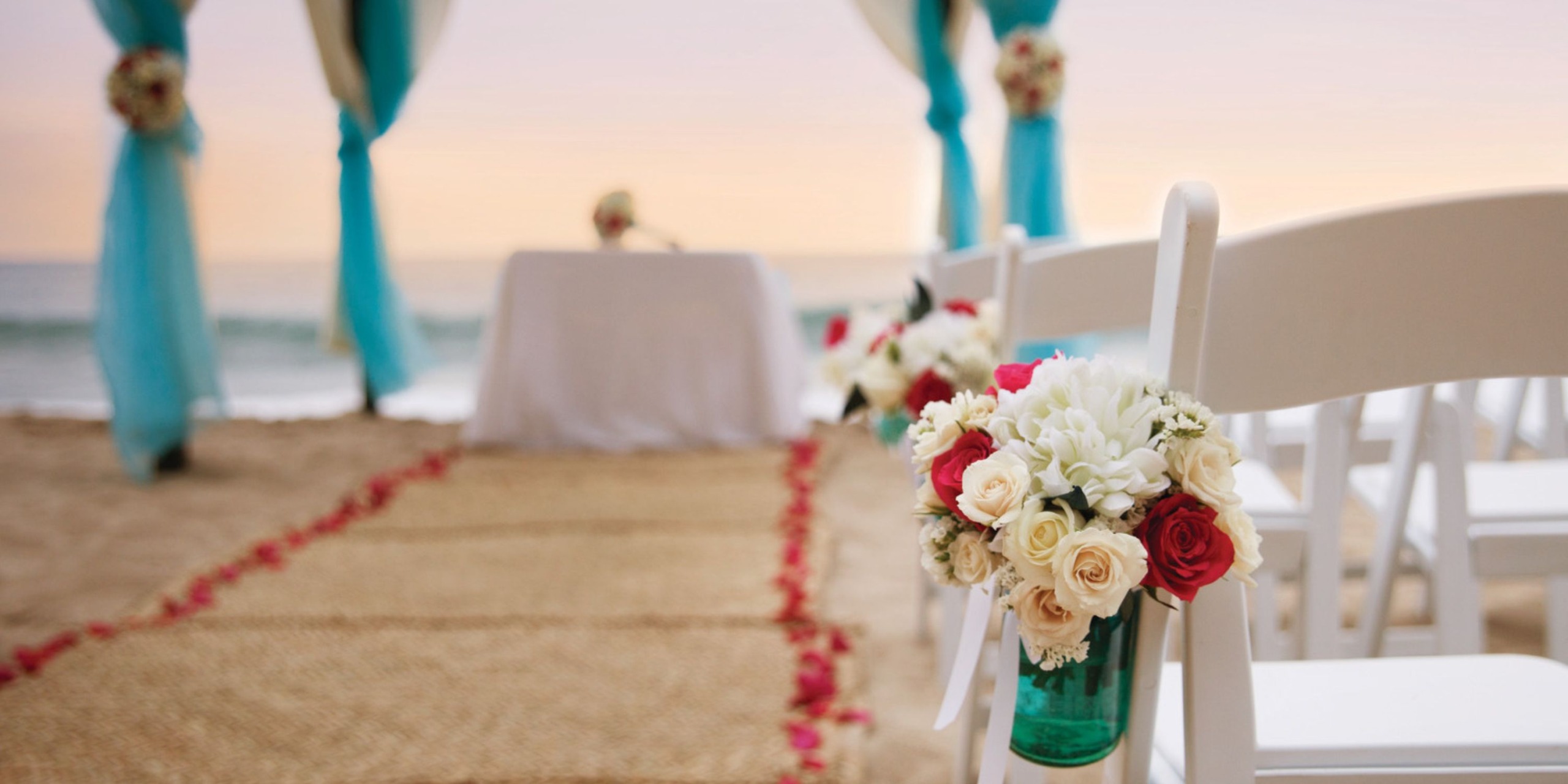 Hyatt Ziva Puerto Vallarta provides an exquisite destination wedding setup featuring chairs, floral arrangements, and a beautifully designed aisle leading to the altar on the beach.