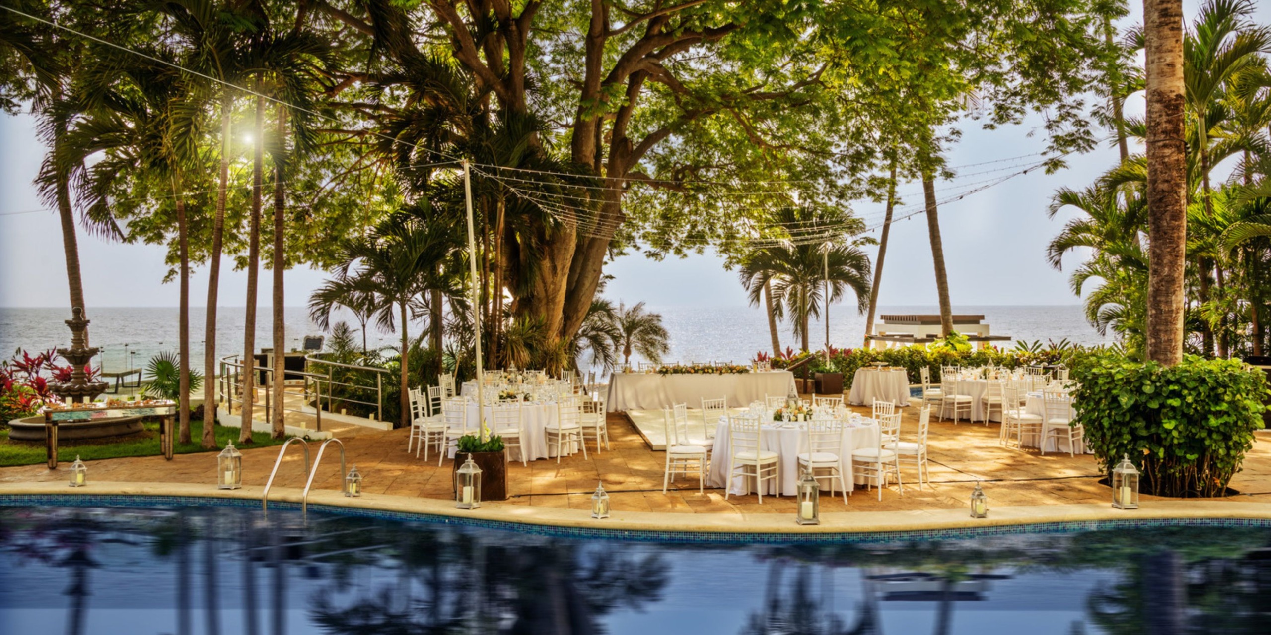 Experience a destination wedding at Hyatt Ziva Puerto Vallarta, where you'll celebrate poolside amidst lush trees and stunning ocean views.