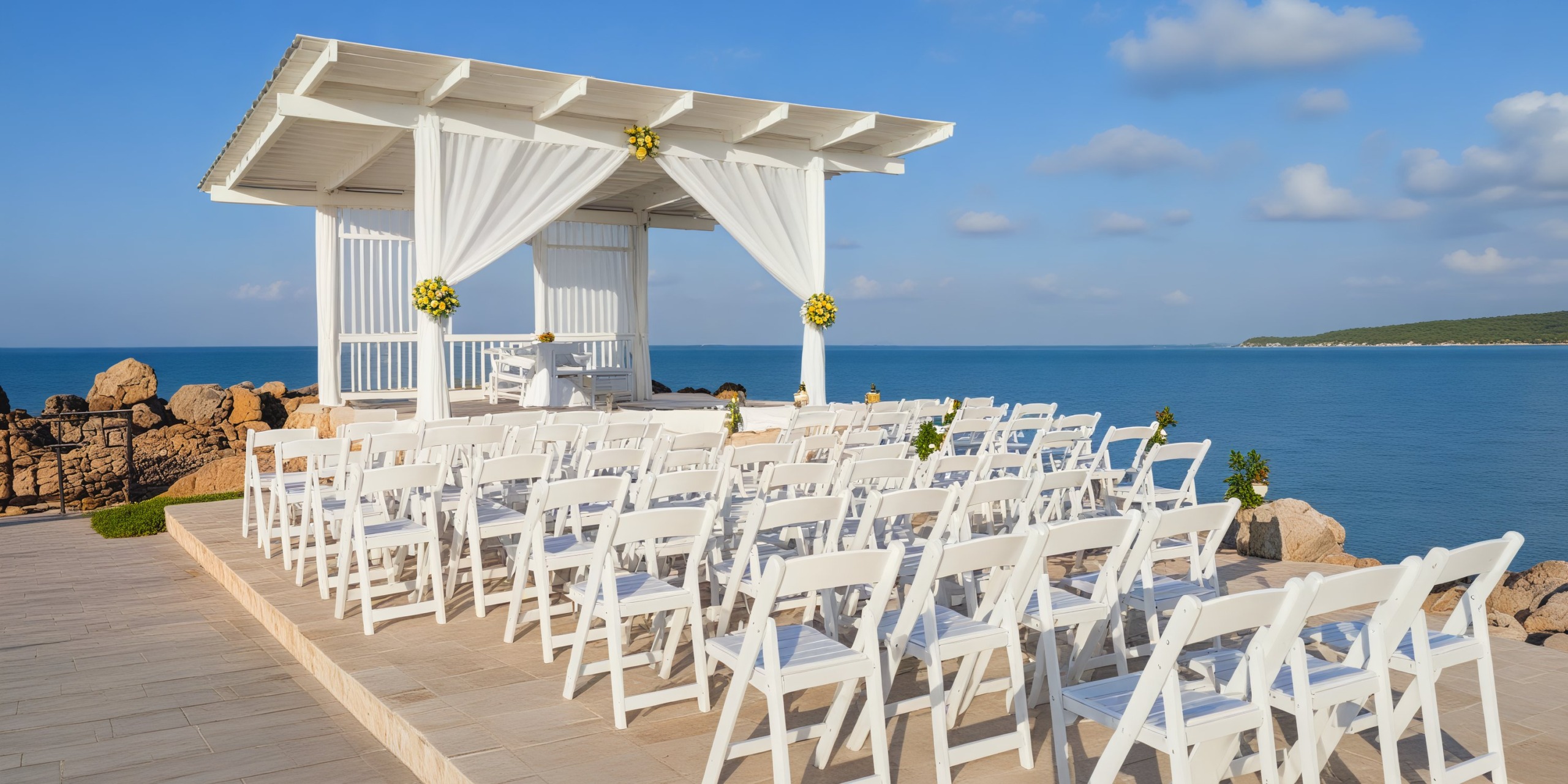 Dream destination wedding setup at Hideaway features pristine white chairs and a charming gazebo with breathtaking ocean views.