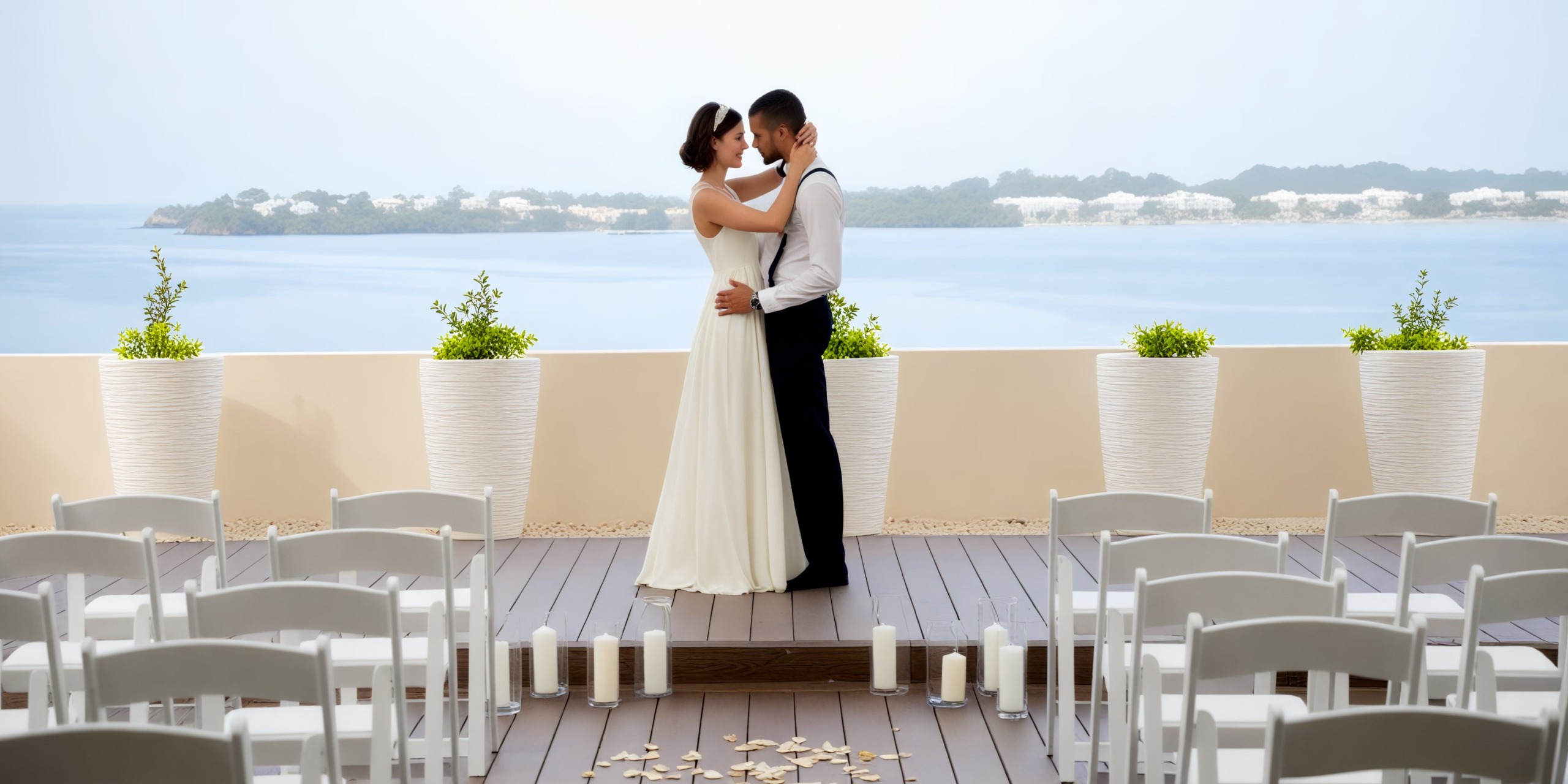 A couple shares a kiss on a deck at Hideaway at Royalton Negril, surrounded by chairs and candles, setting the perfect scene for a romantic destination wedding.