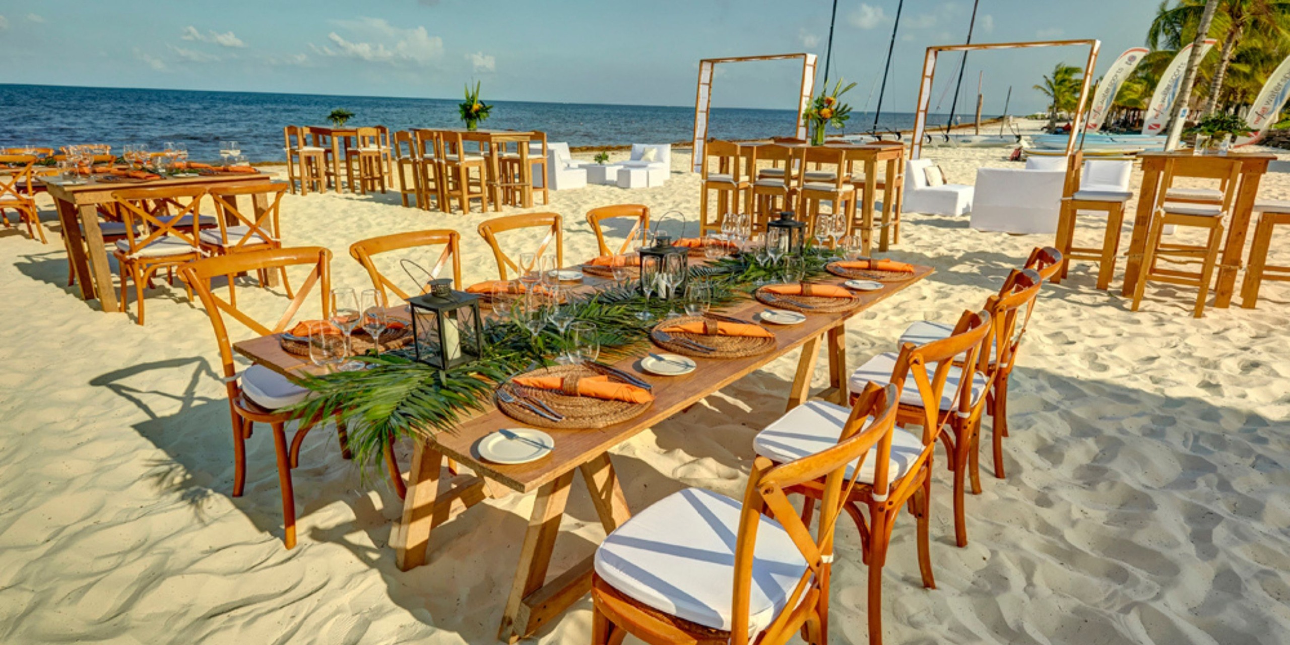 Experience beachfront dining at Hideaway Royalton, where you and your wedding guests can enjoy wood tables and chairs set on the sand with stunning ocean views—a perfect setting for a memorable destination wedding celebration.