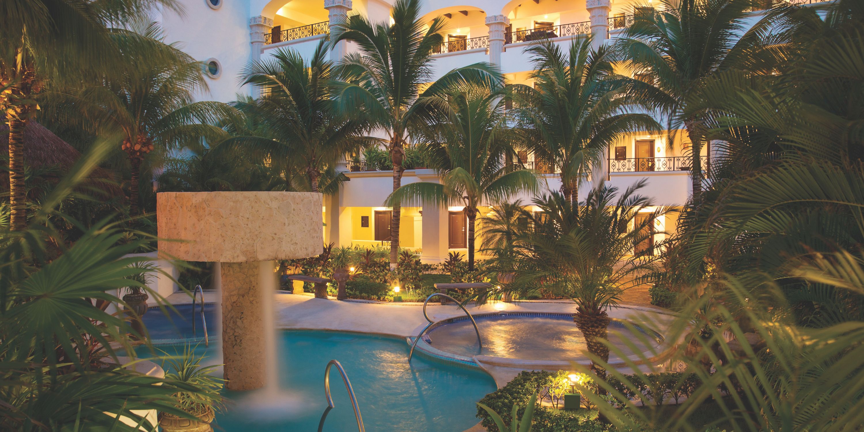 Hyatt Zilara Cancun’s pool, ideal for a destination wedding, glows at dusk amid palms and balconies.