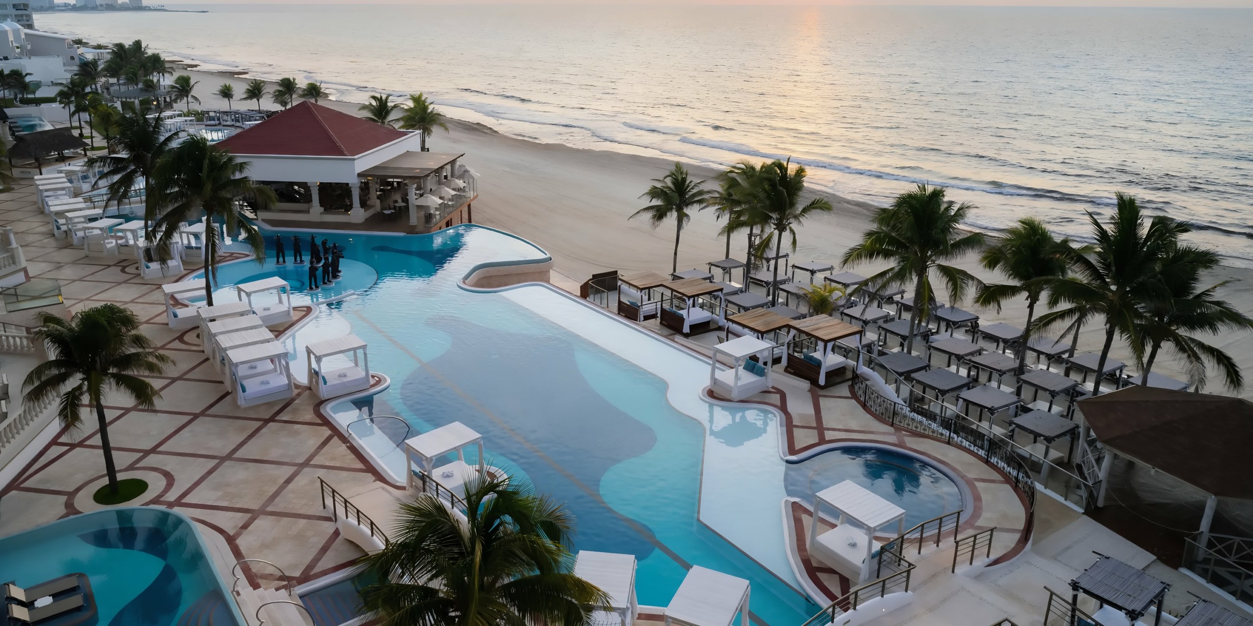 Aerial view of the Hyatt Zilara Cancun swimming pool and bar next to a beach at sunrise.