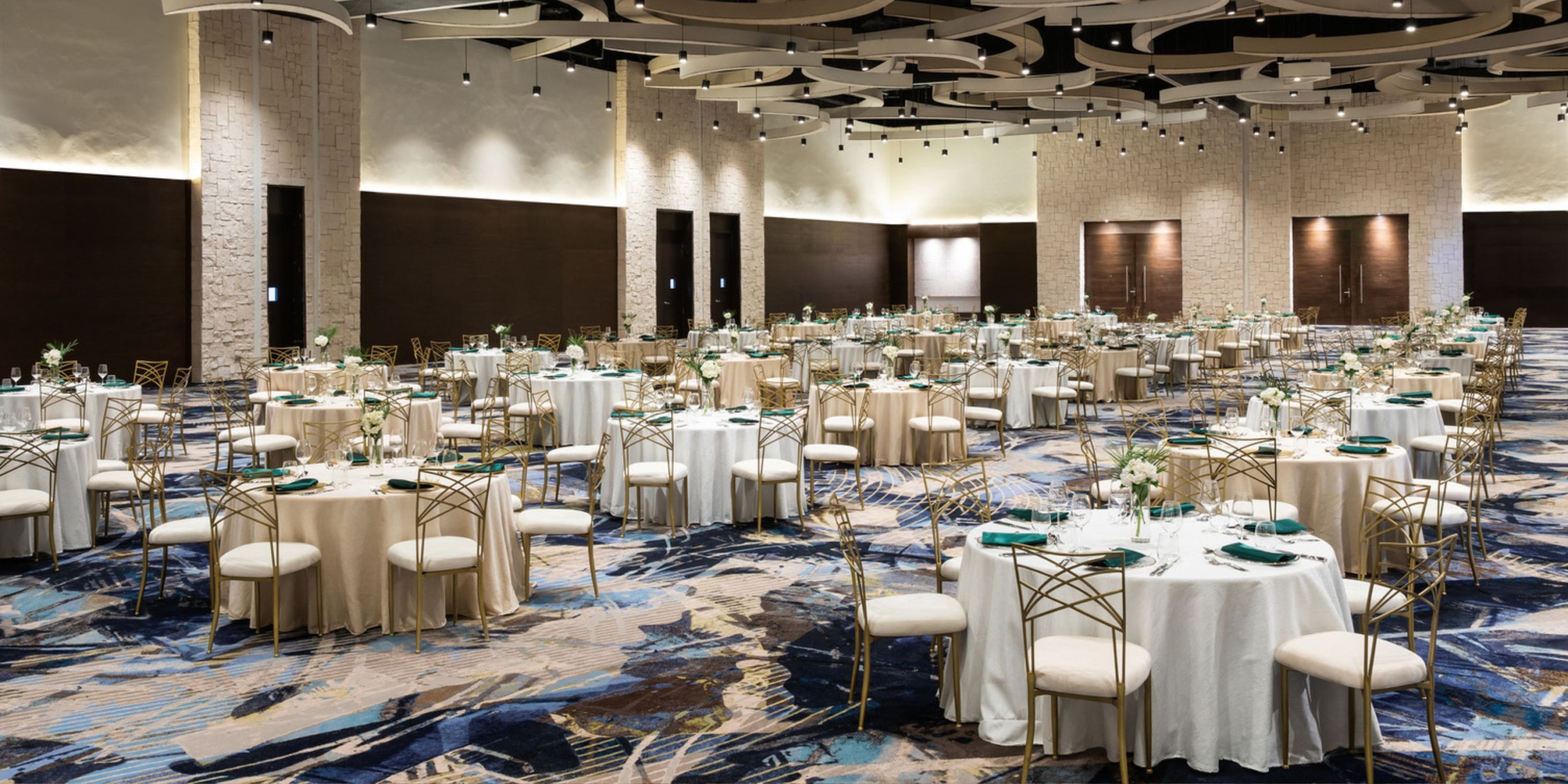 A sophisticated banquet hall adorned with round tables and chairs, beautifully arranged for a destination wedding event.